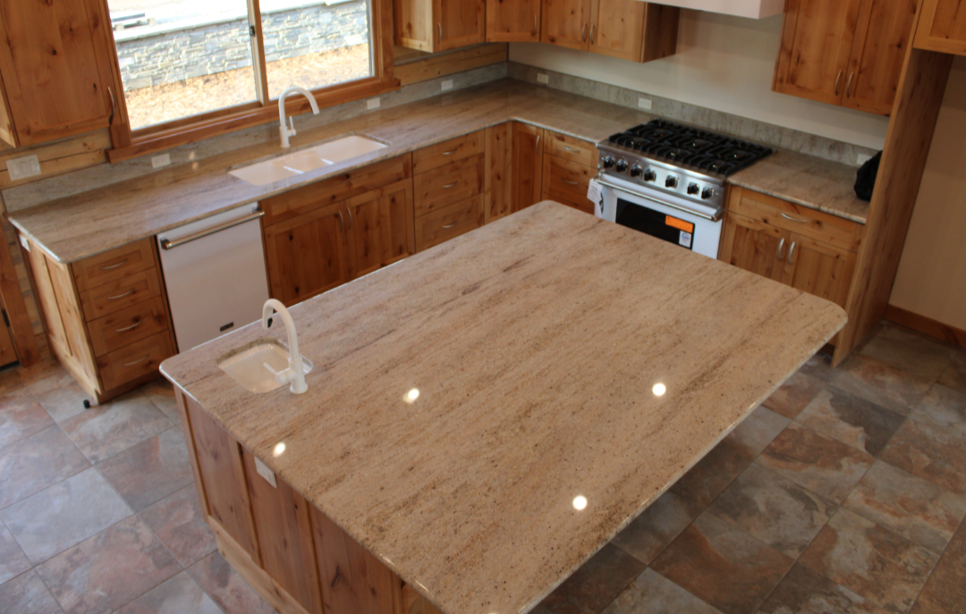 Kitchen with wooden cabinets, granite countertops, a large center island with a sink, and a gas stove.
