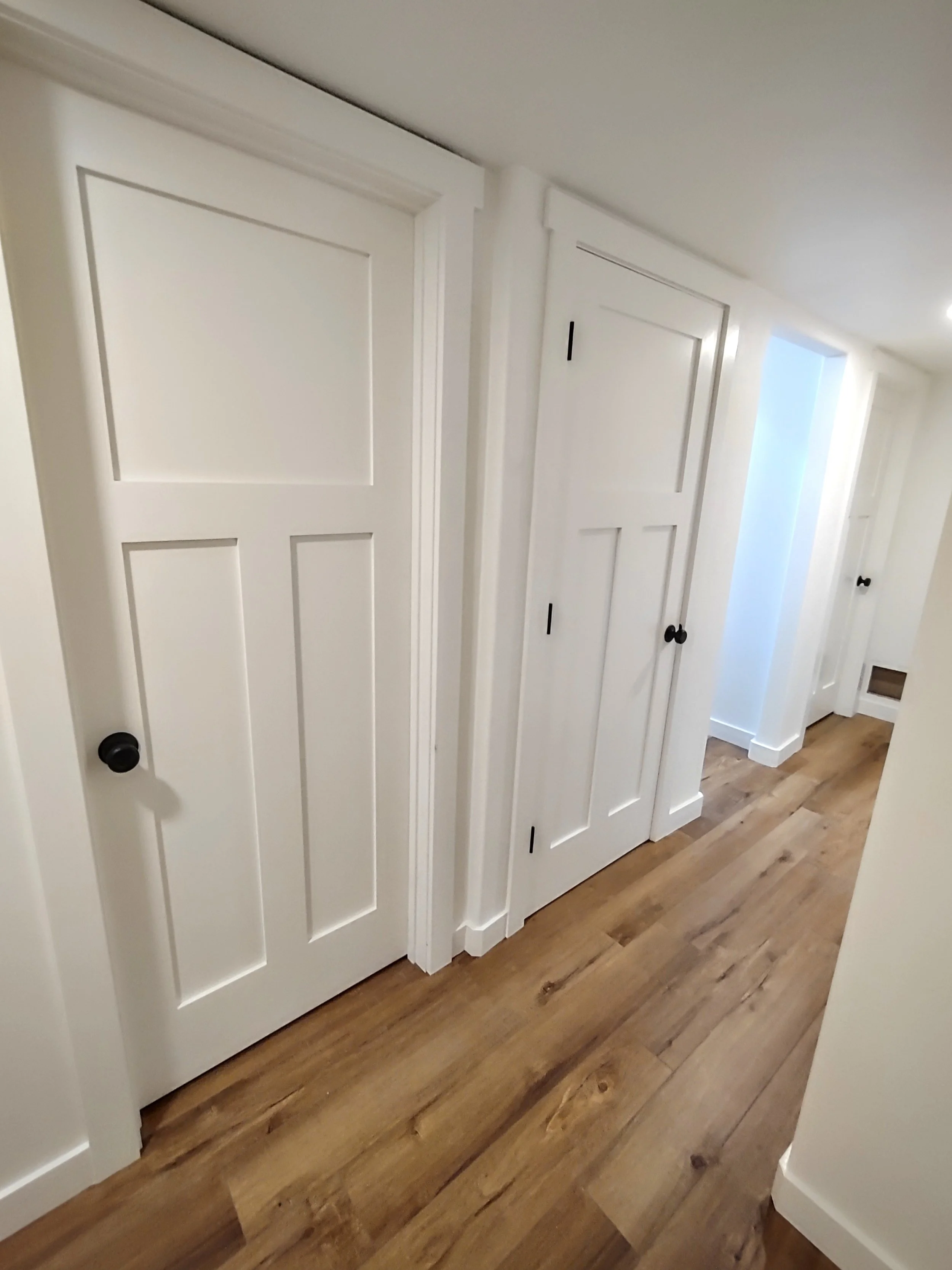 White interior doors and wooden flooring in a hallway.