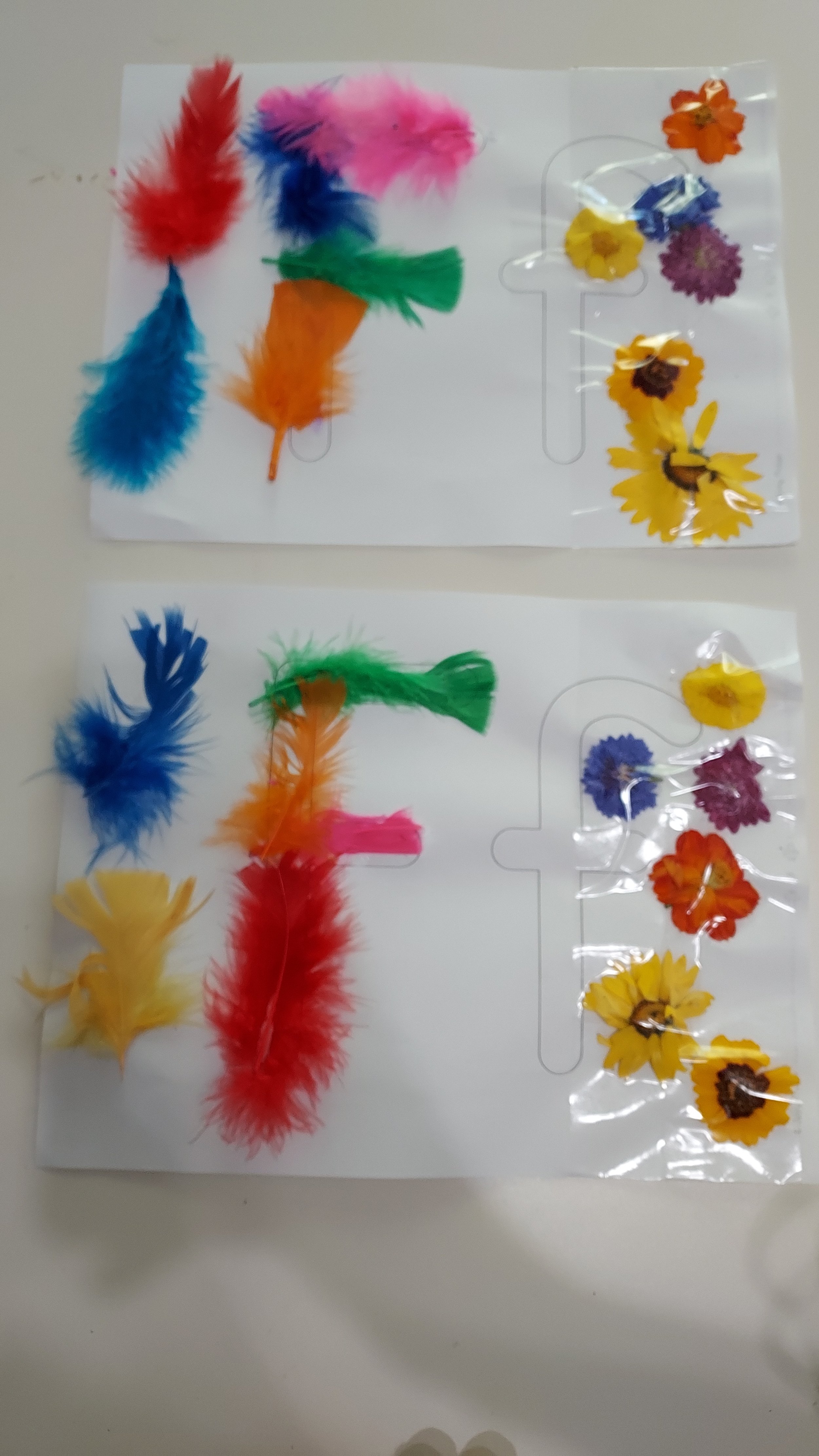 Two sheets of colorful feather and flower stickers inside plastic packaging