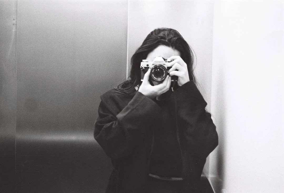 Person taking a photo with a camera in an elevator.