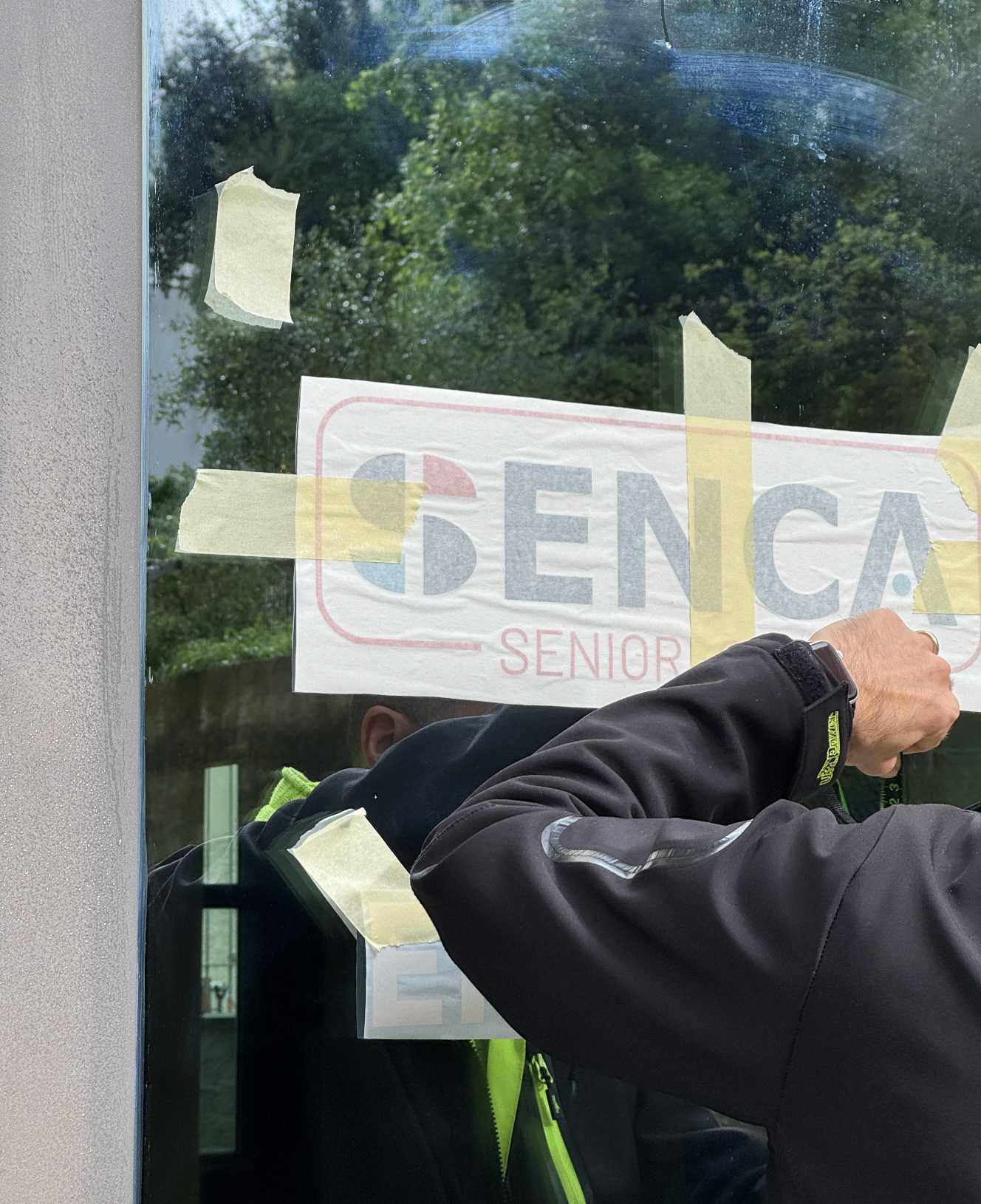 Persona che attacca un adesivo con scritto su una vetrina