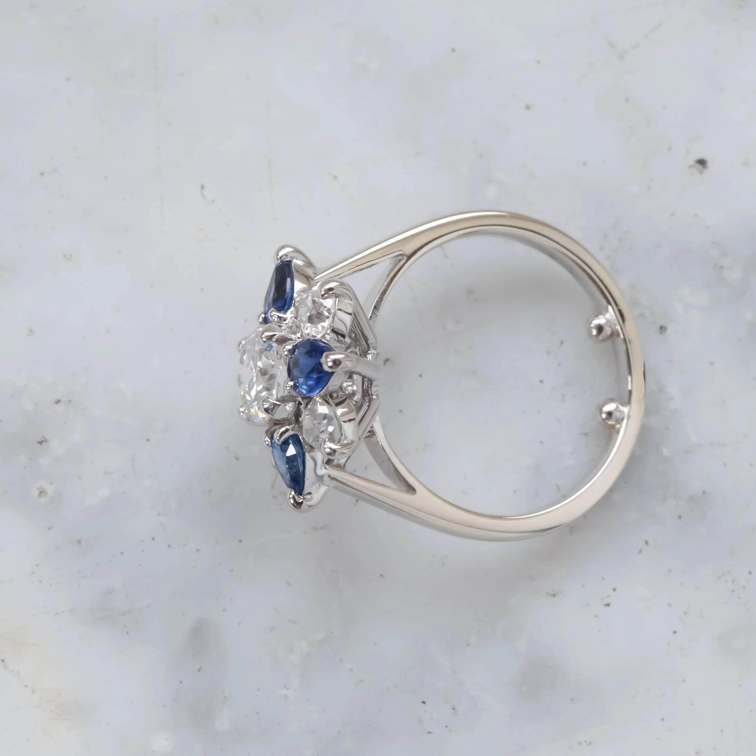 Vue de profil Bague en or blanc ornée de diamants et de saphirs bleus.