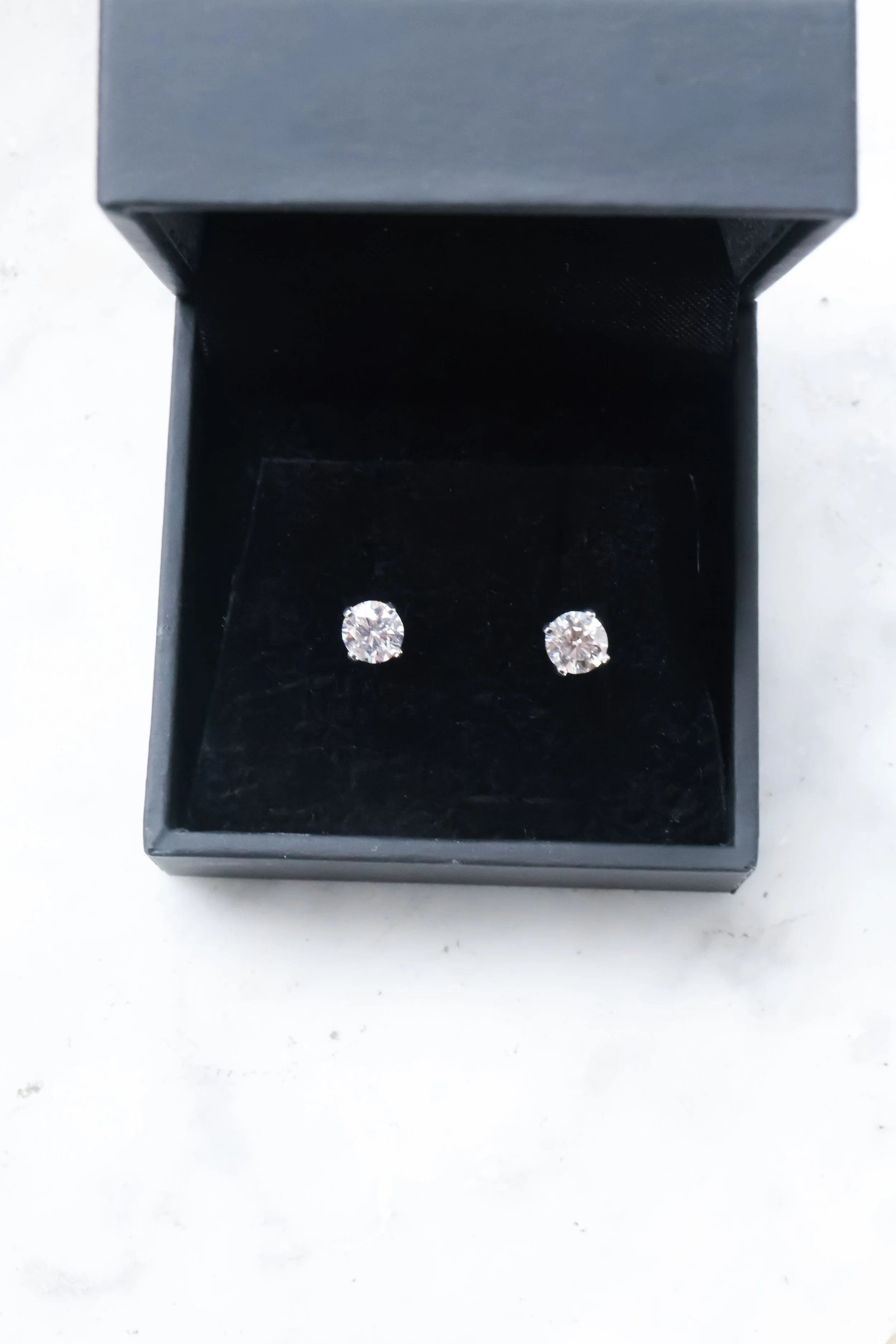 Une paire de boucles d'oreilles avec des diamants dans une boîte noire.