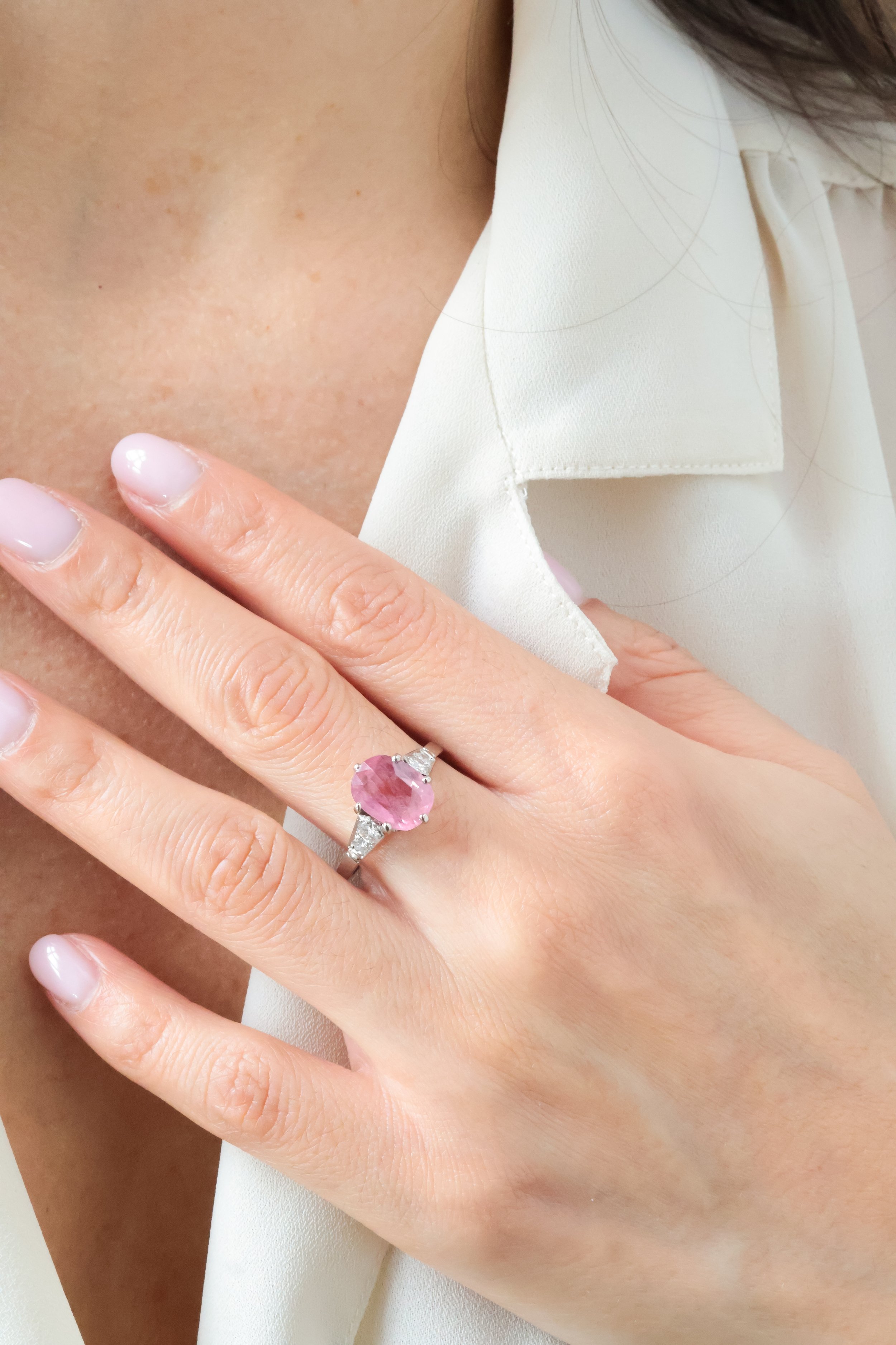 Main d'une femme portant une bague avec un grand pierre rose sur l'annulaire gauche.