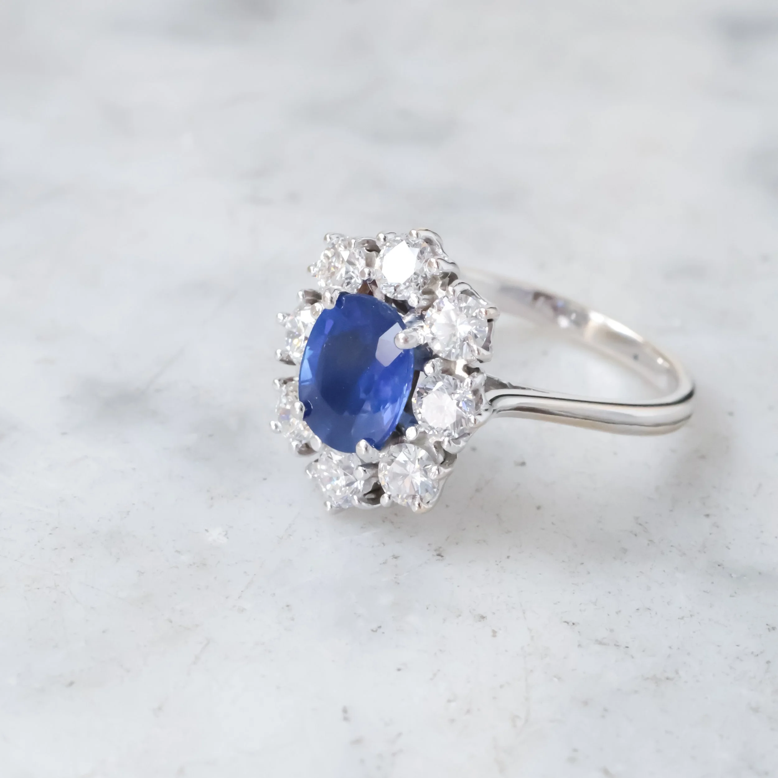 Bague ancienne en or blanc sertie d’un saphir ovale entouré de diamants