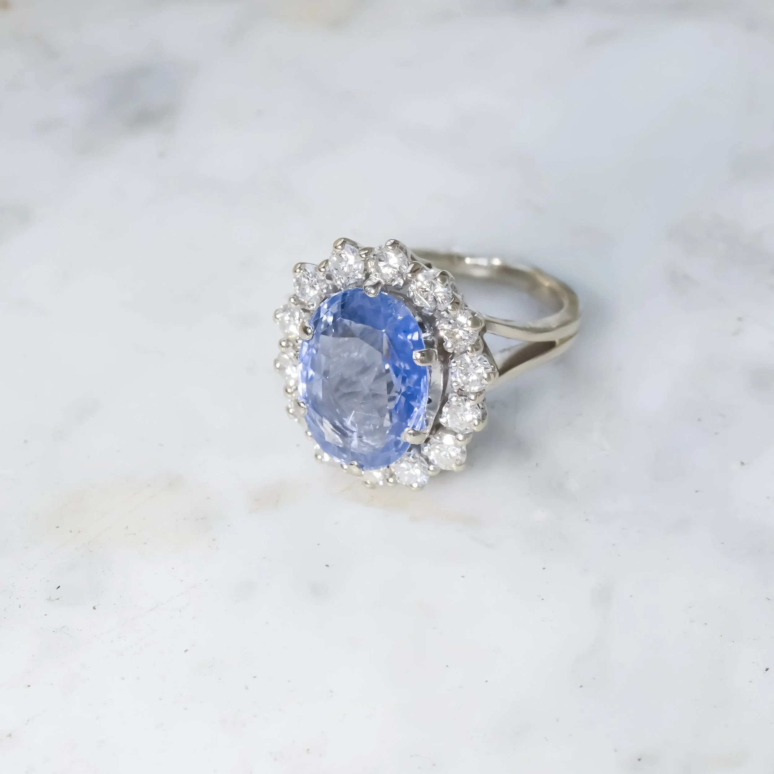 Une bague en argent avec un gros saphir ovale entouré de diamants.