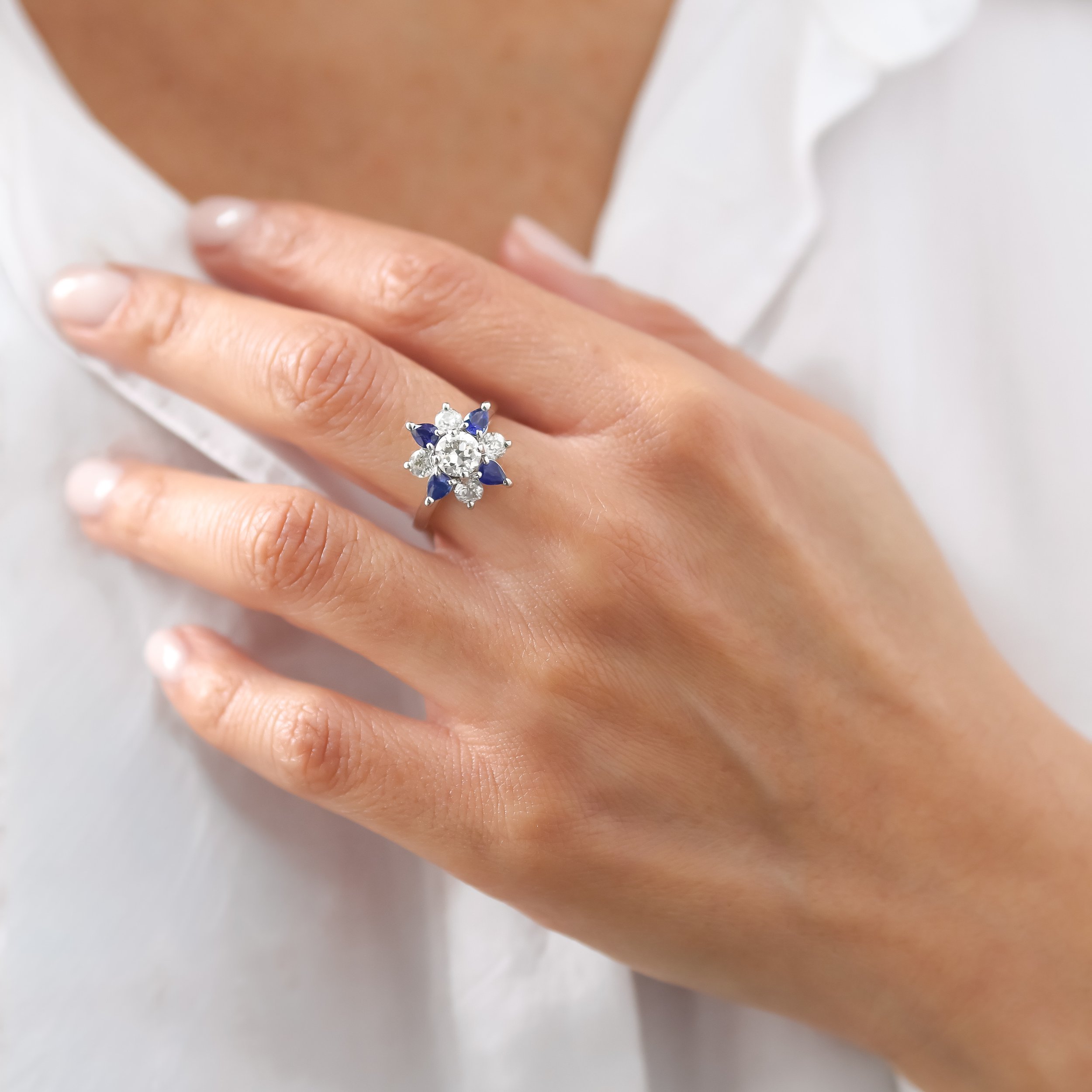 Main présentant une bague or blanc ornée de diamants et de saphirs .