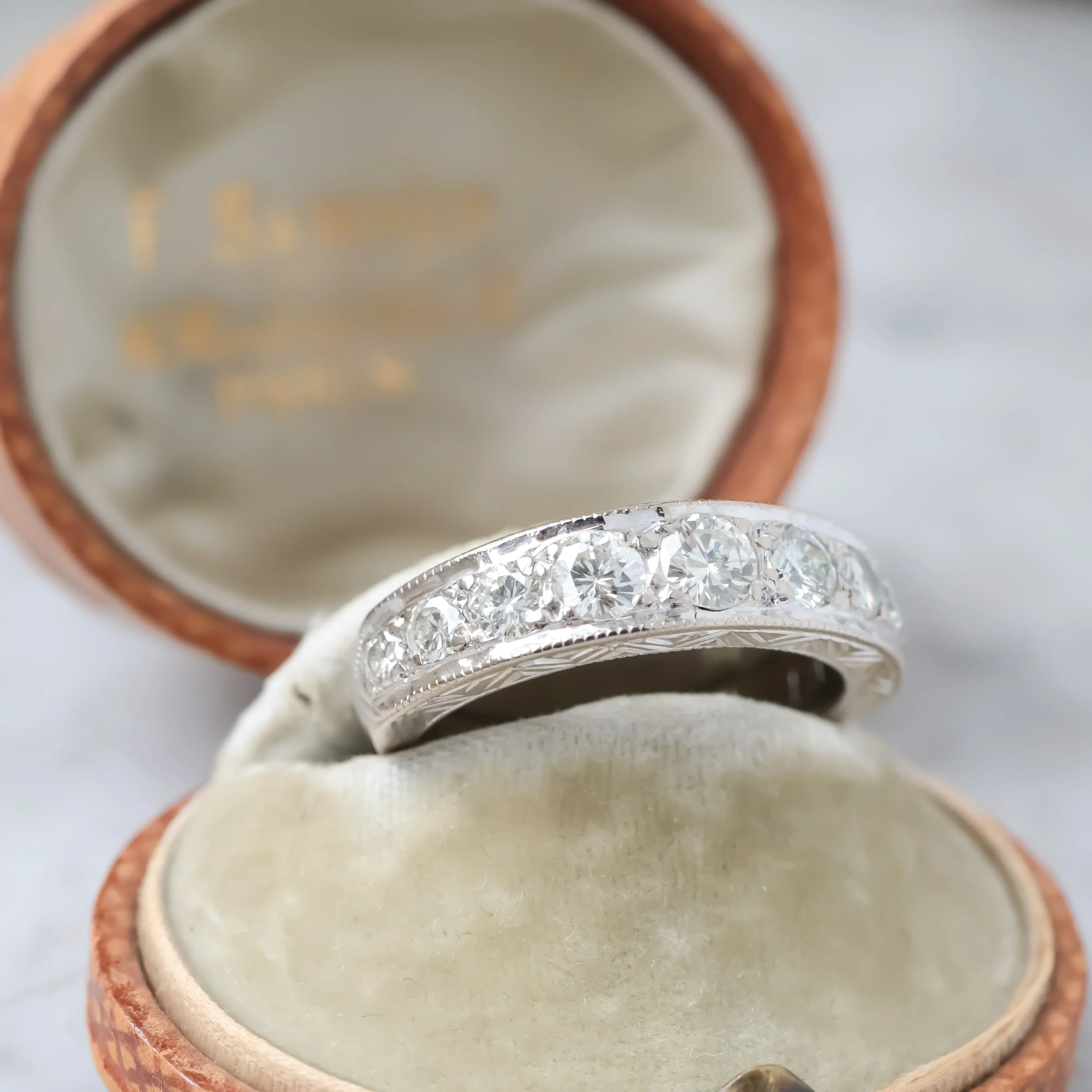 Demi alliance ancienne art déco ornée de diamants posée dans un écrin, vue de profil