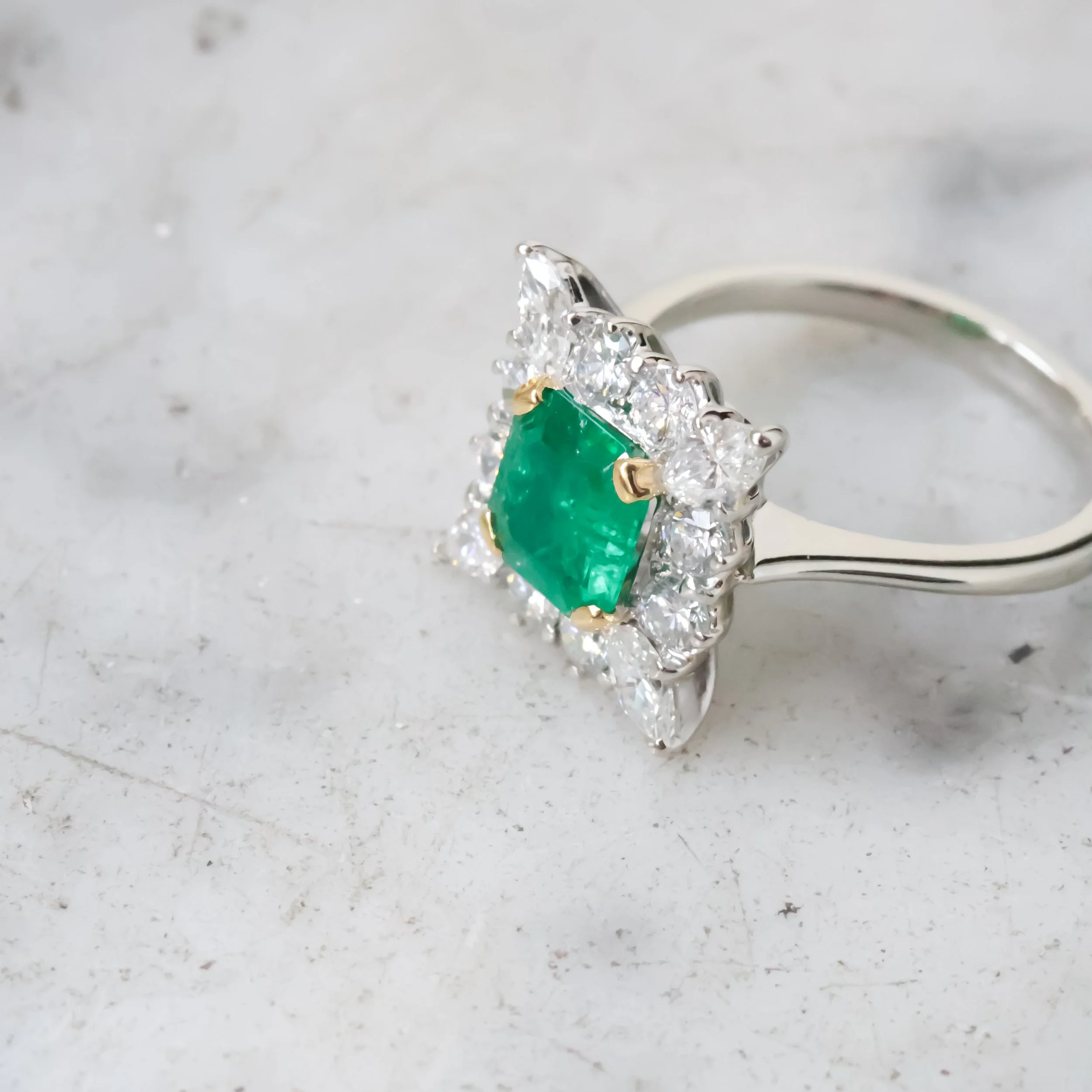 Bague ancienne en or blanc sertie d’une émeraude carrée entourée de diamants