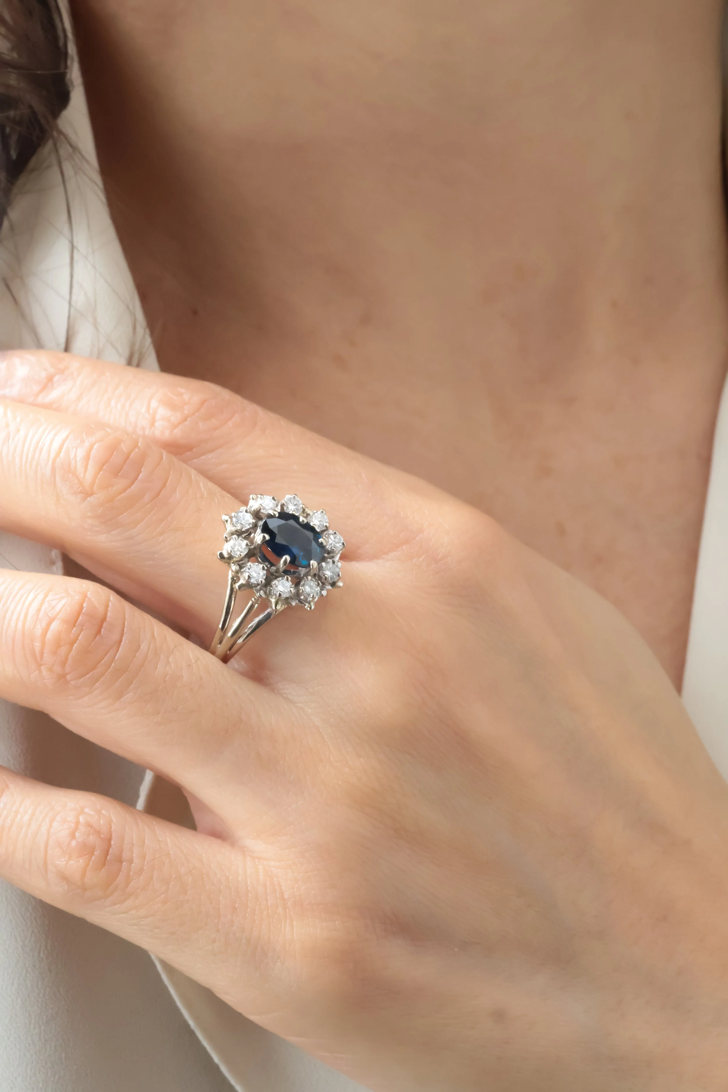 Anneau en or blanc avec un gros saphir noir entouré de diamants sur le doigt d'une femme, porté sur l'annulaire gauche.