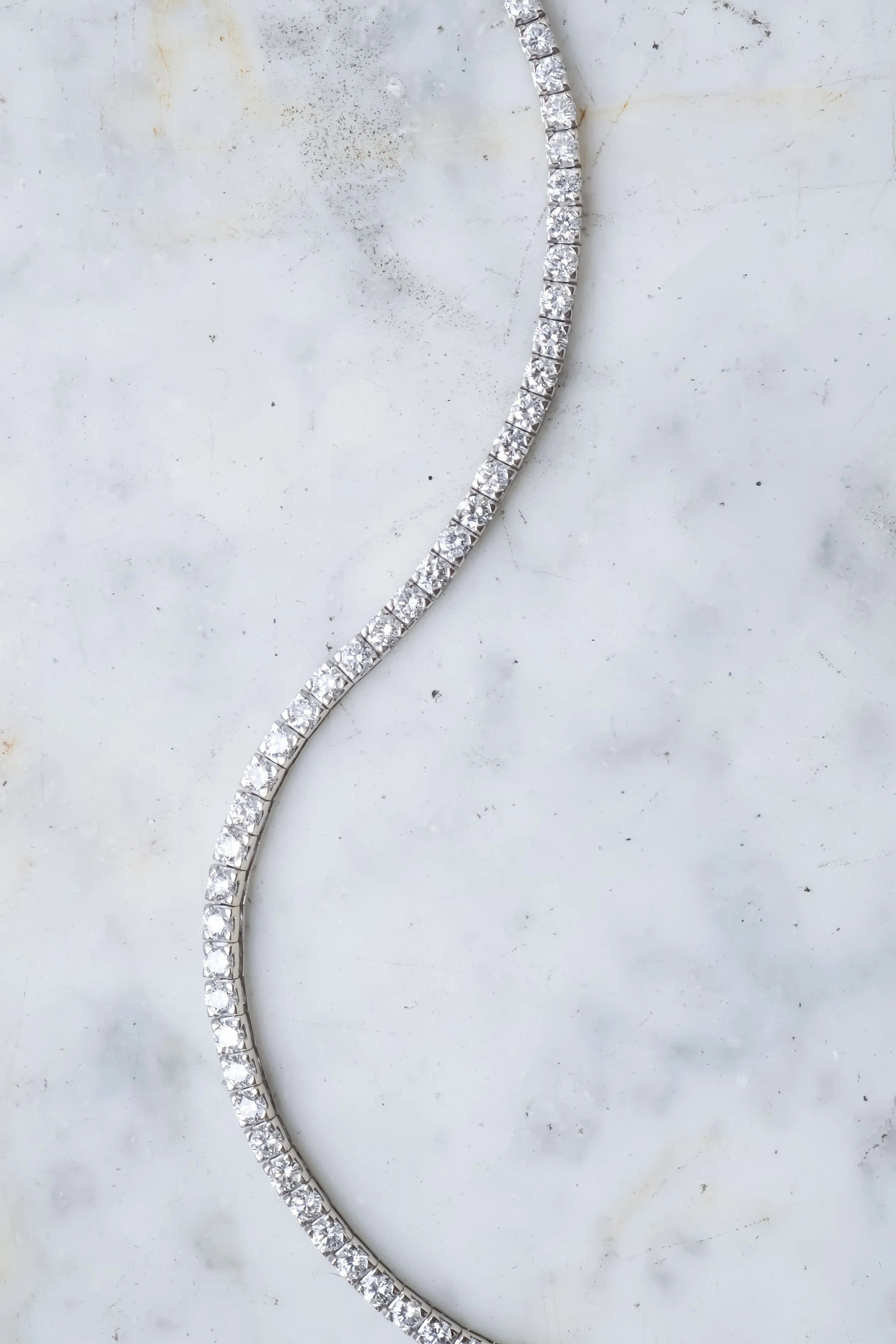 Bandeau de diamants brillants posé sur une surface blanche.