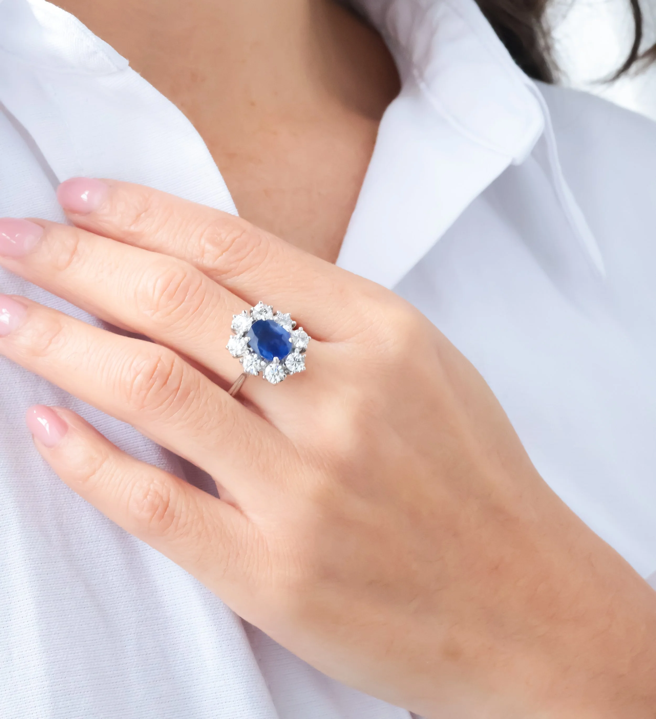 Bague ancienne en or blanc sertie d’un saphir ovale bleu et de diamants, portée à la main