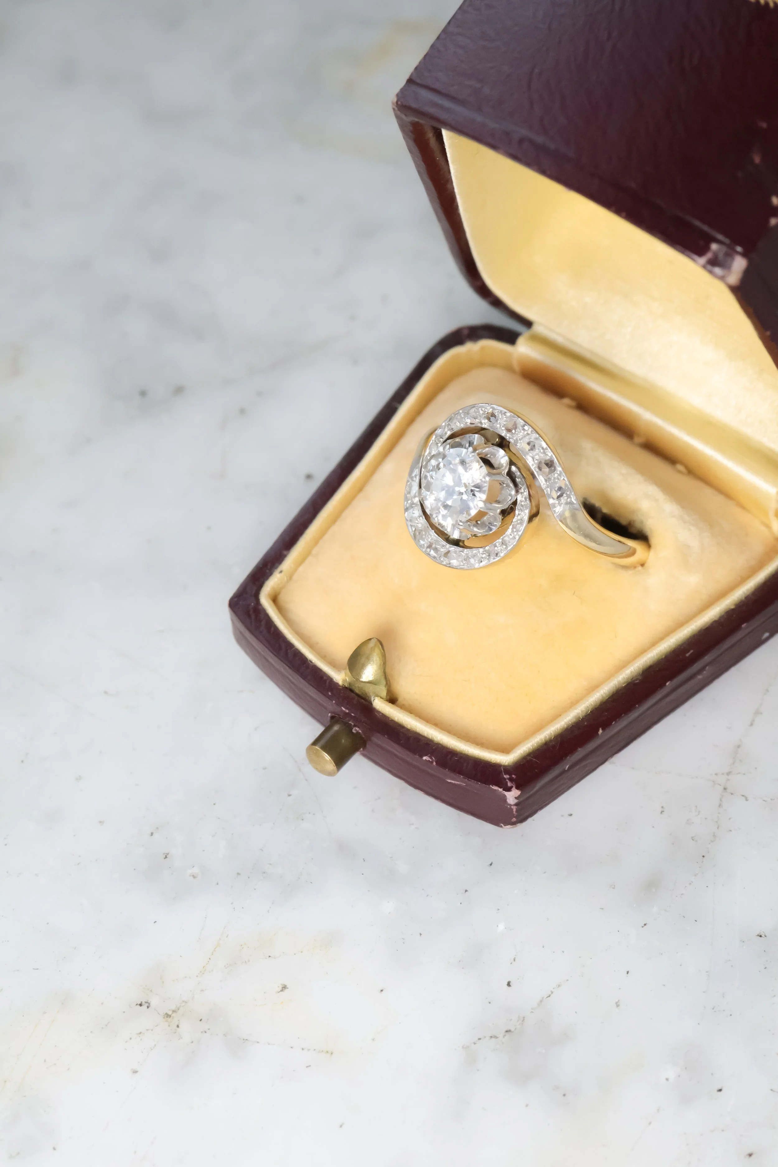 Bague ancienne tourbillon en or ornée de diamants, présentée dans un écrin ancien en bois, vue de côté 