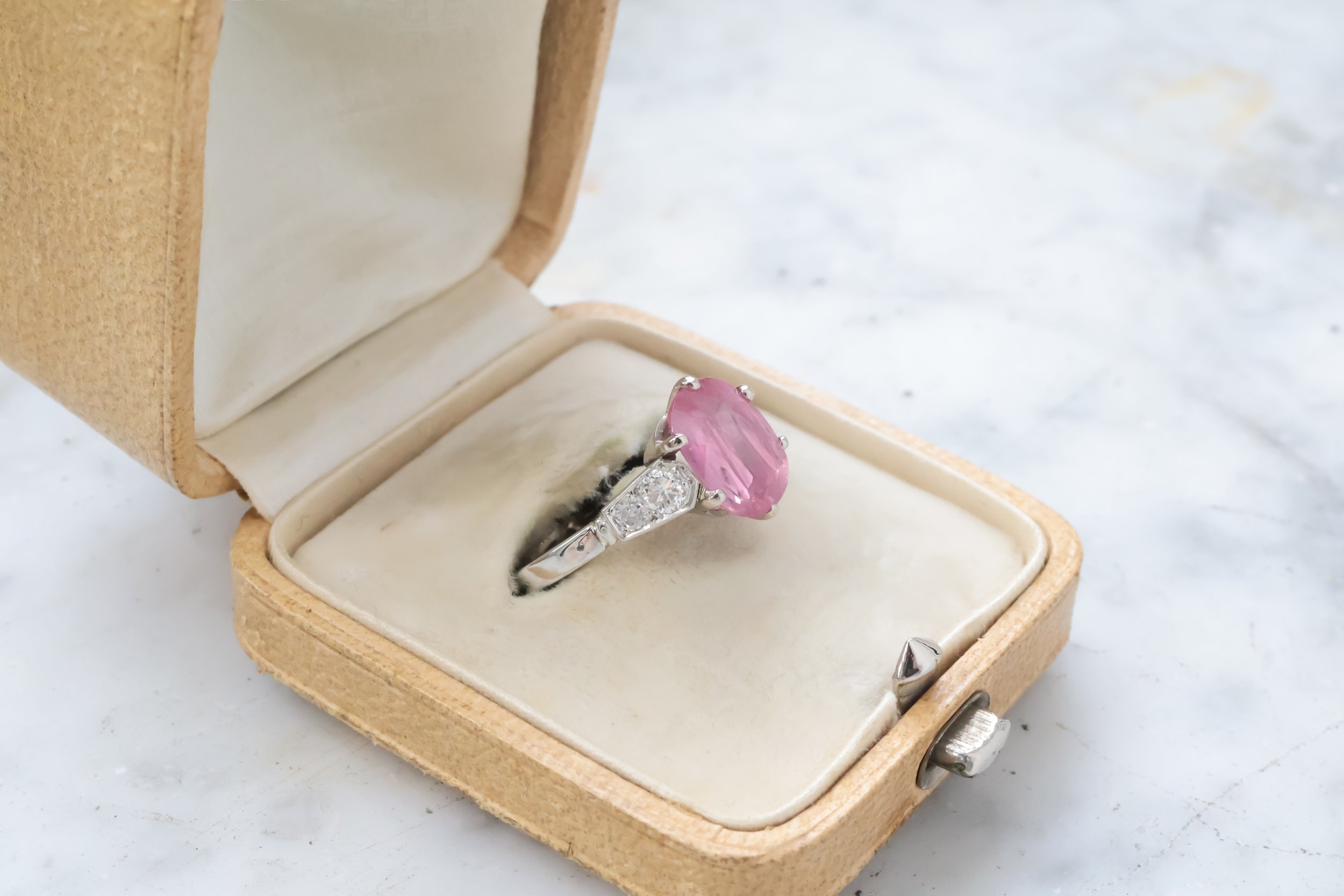 Une bague avec un gros pierre rose dans une boîte à bijoux