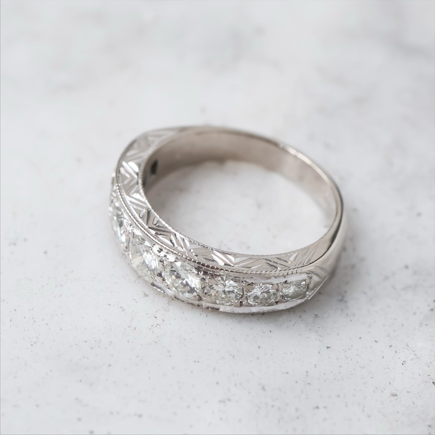 Demi alliance ancienne art déco ornée de diamants posée sur un support en marbre , vue de profil