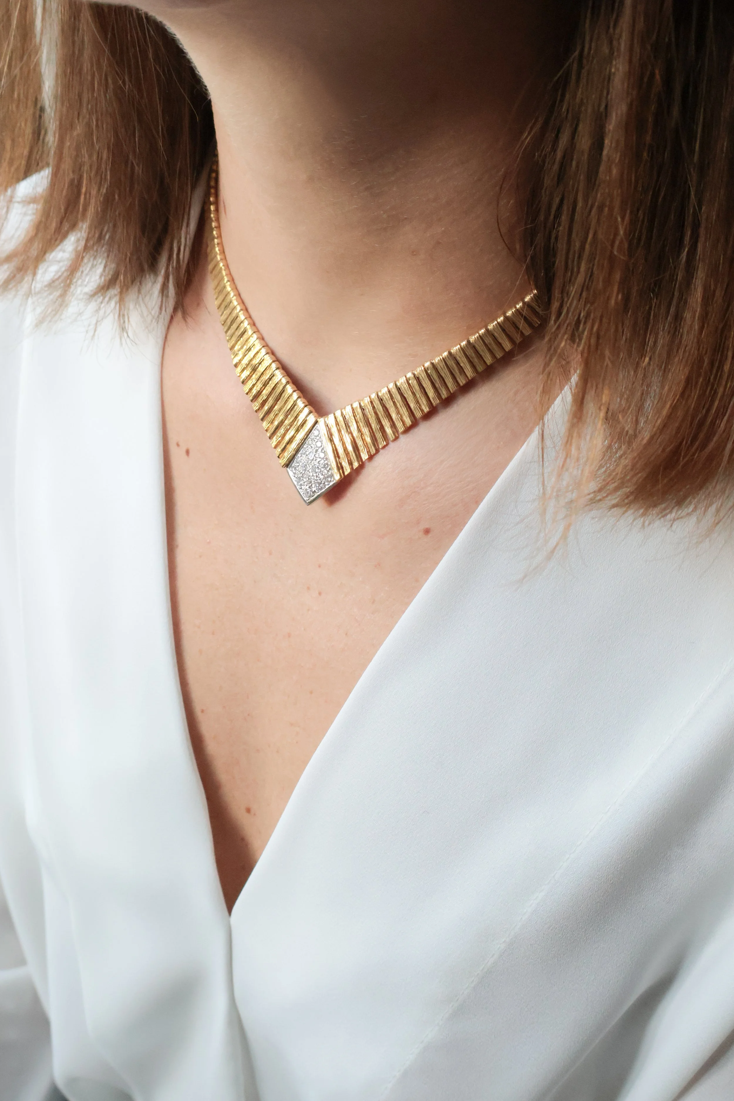 Collier en or avec un pendentif en or pavé de diamants porté par une femme.