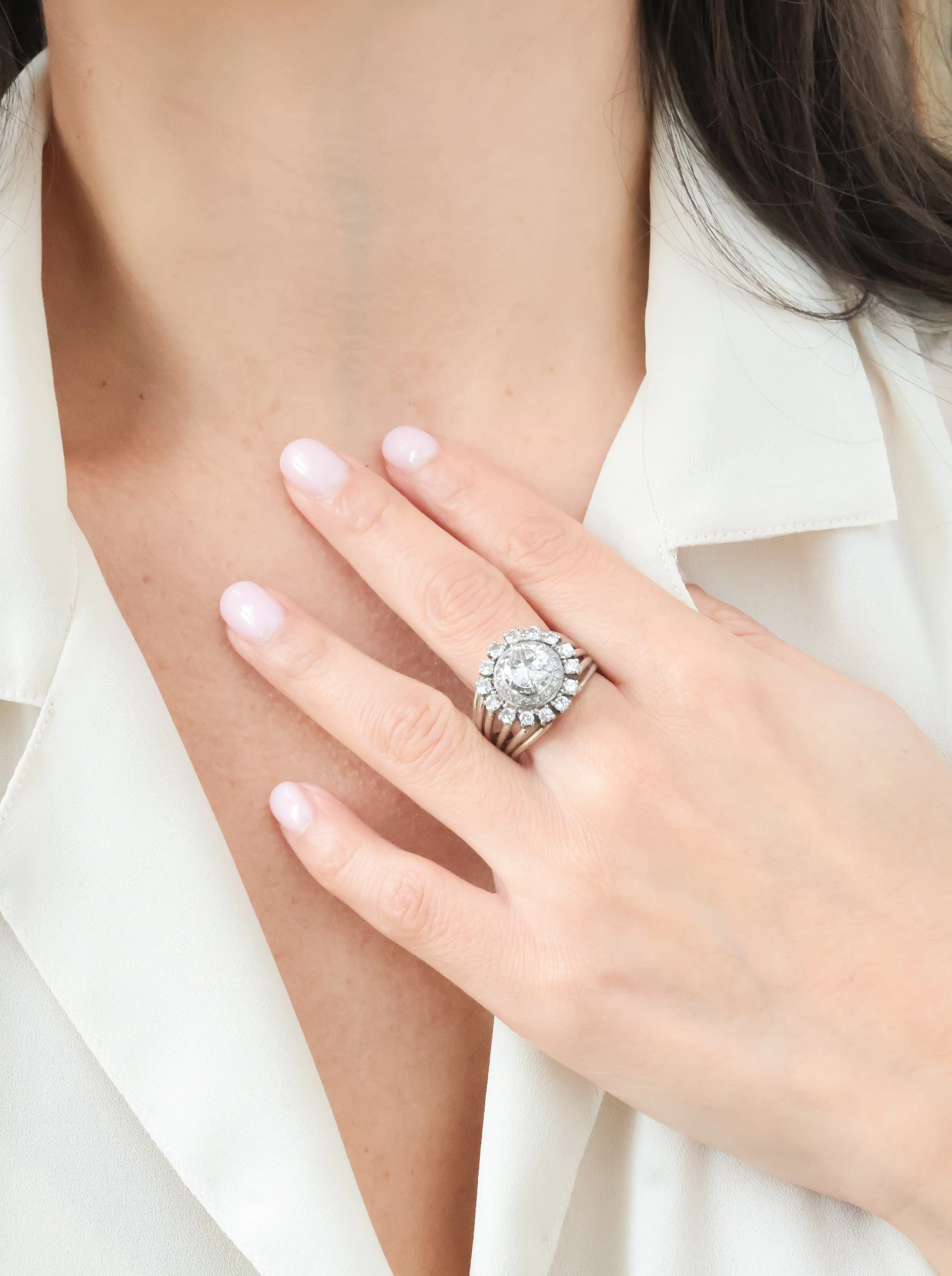 Une main portant une bague en diamant, posée sur la poitrine d'une personne.