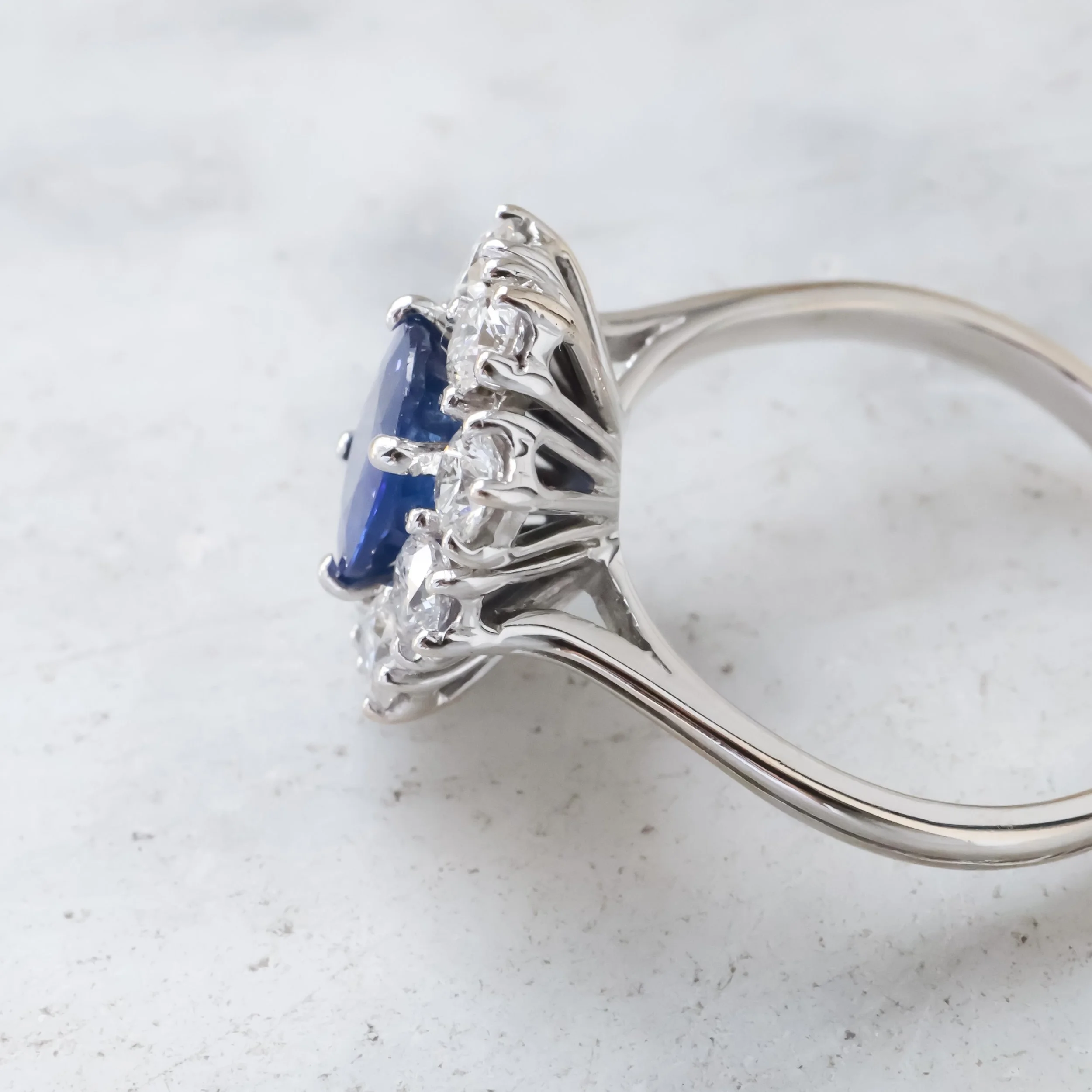 Bague ancienne en or blanc, saphir ovale bleu central entouré de diamants, vue de profil