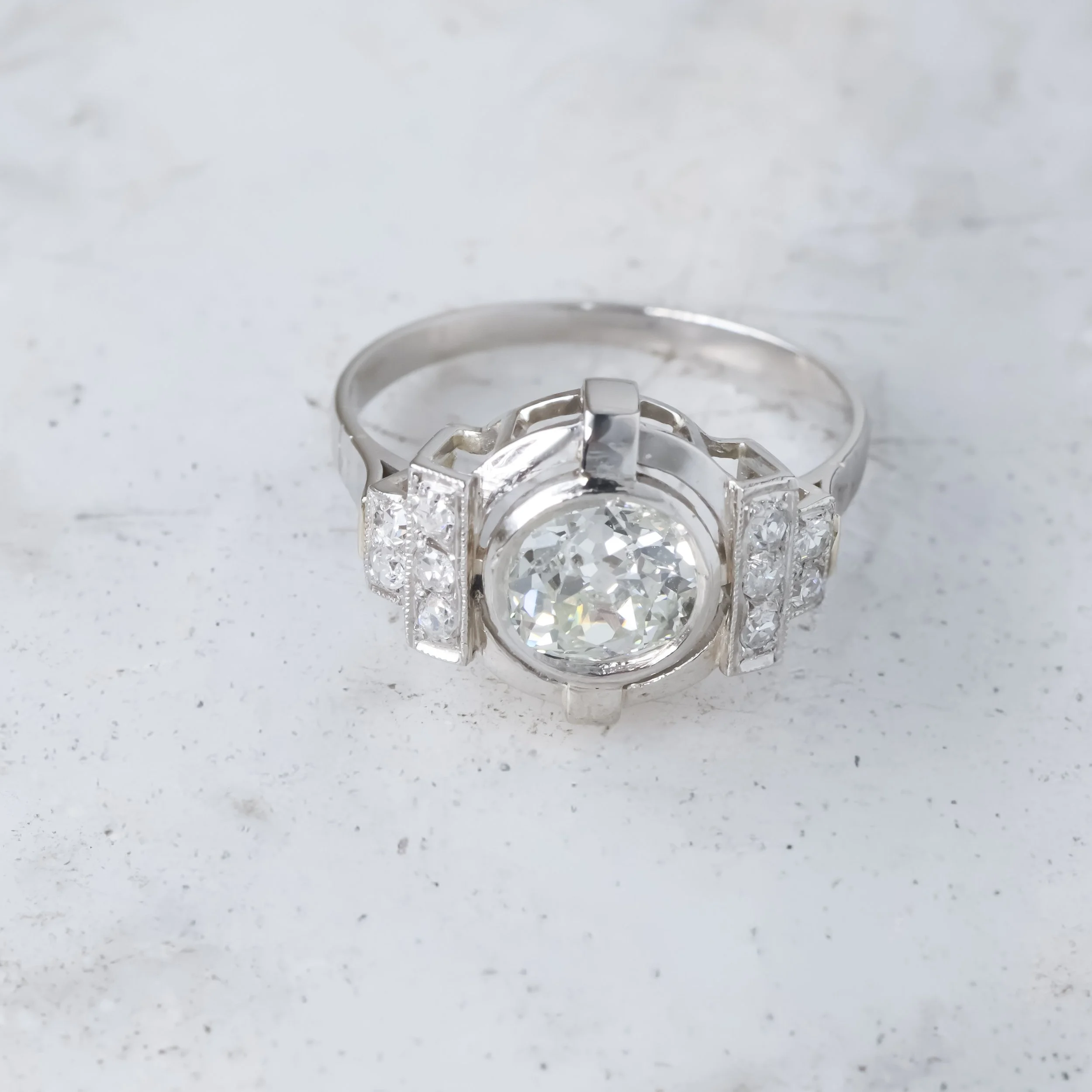 Bague ancienne d'époque art déco avec diamants posée sur du marbre 