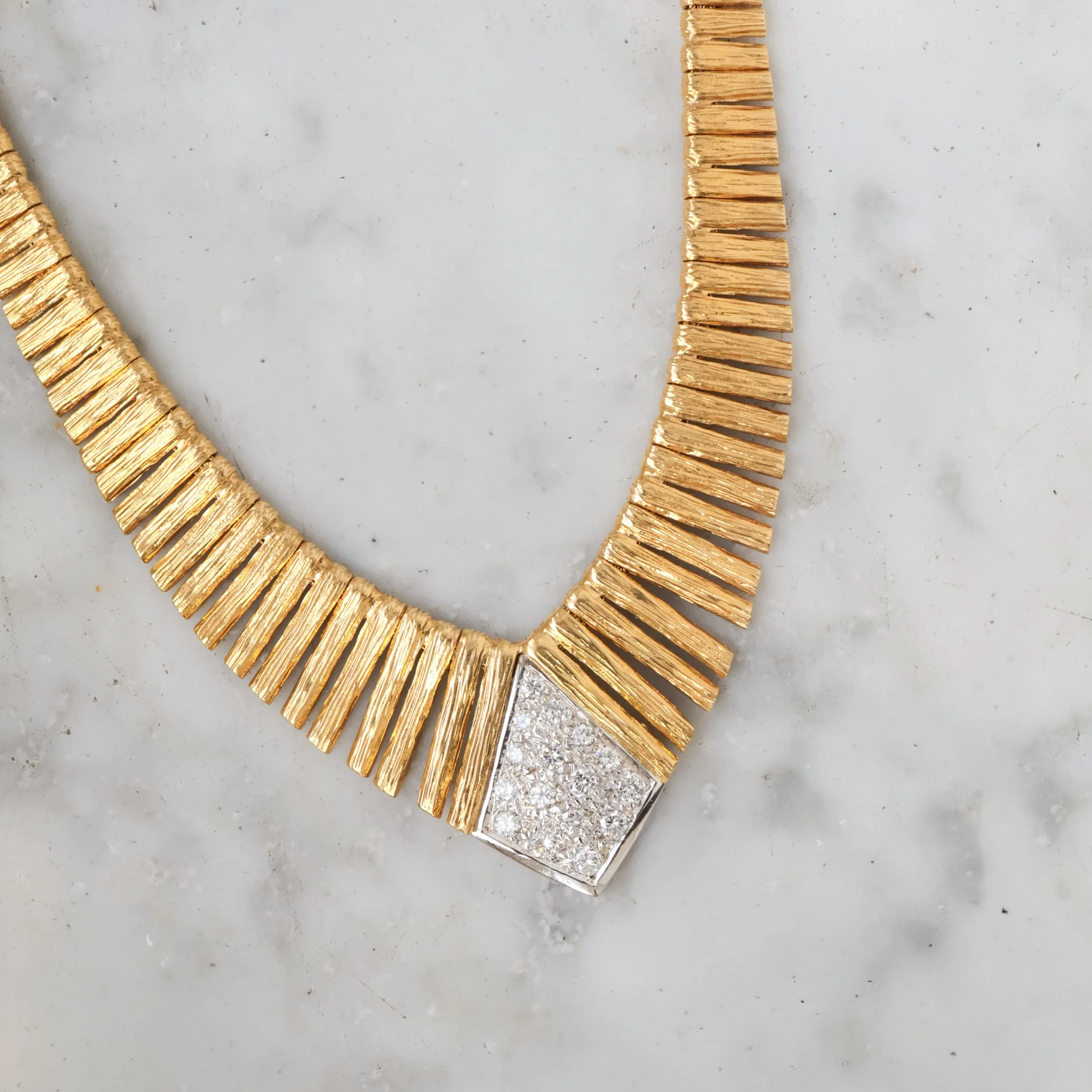 Collier doré avec une pièce centrale pavée de diamants.