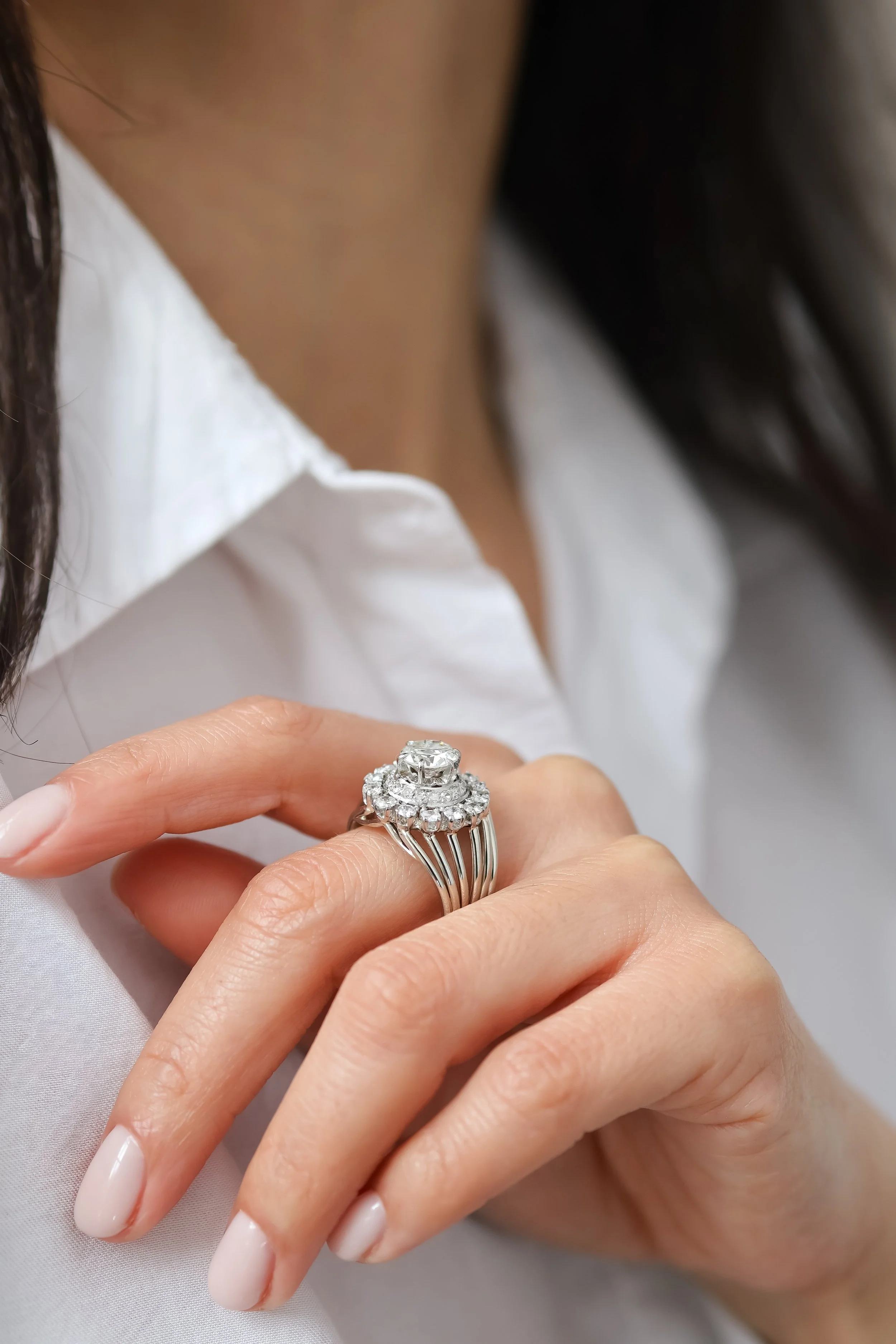 Une femme portant un chemisier blanc, portant une bague en diamant sur le doigt, avec une peau claire et des ongles soignés