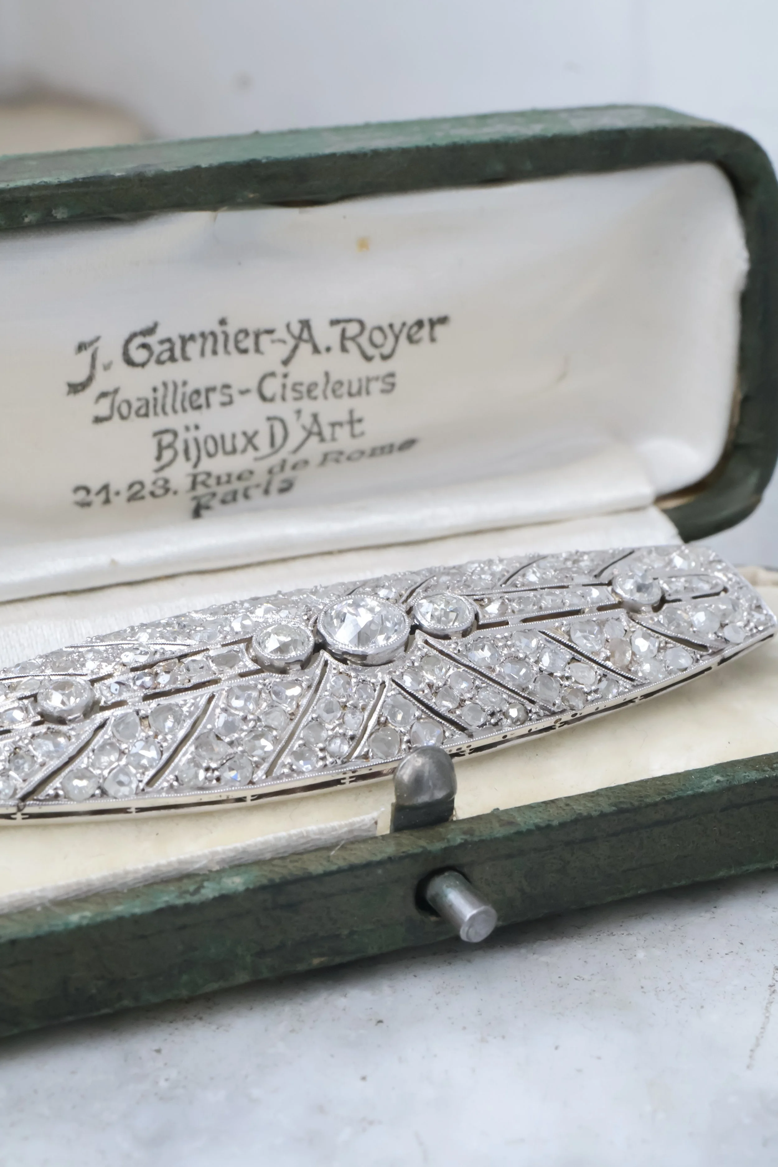 Une boîte à bijoux vintage contenant une broche ancienne ornée de diamants.