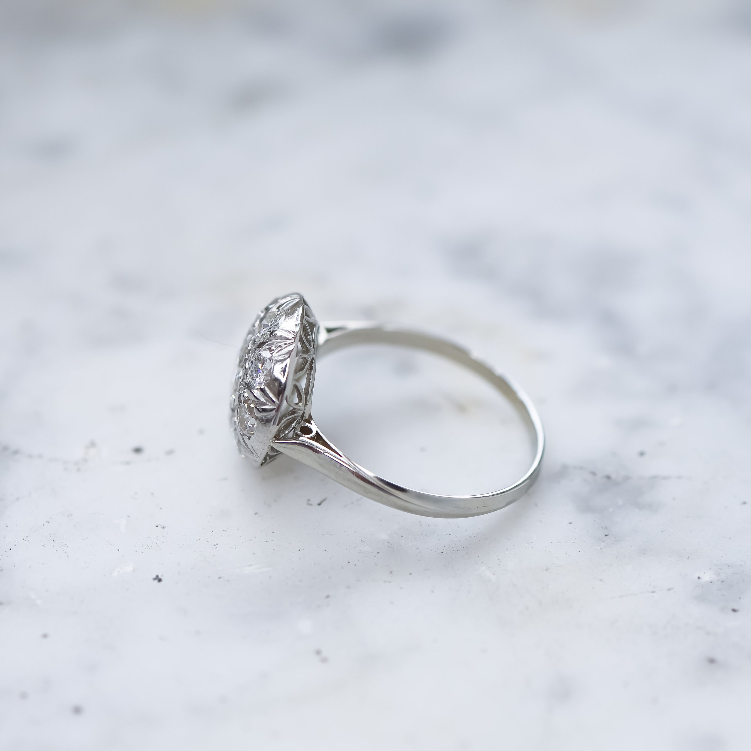 Bague en argent avec une pierre précieuse transparente sur un fond blanc cassé.