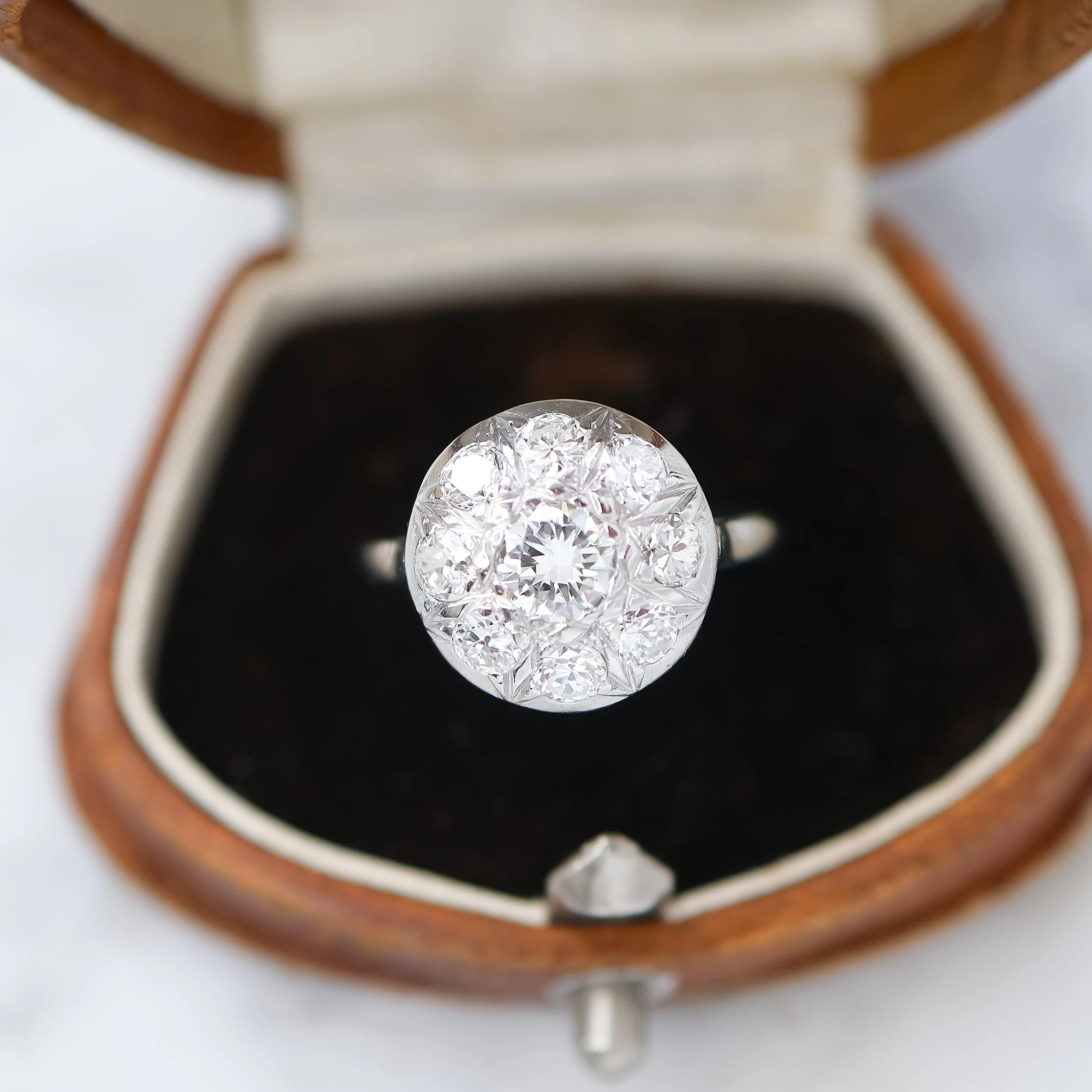 Bague en or avec un grand product de plusieurs diamants dans une boîte en cuir marron.