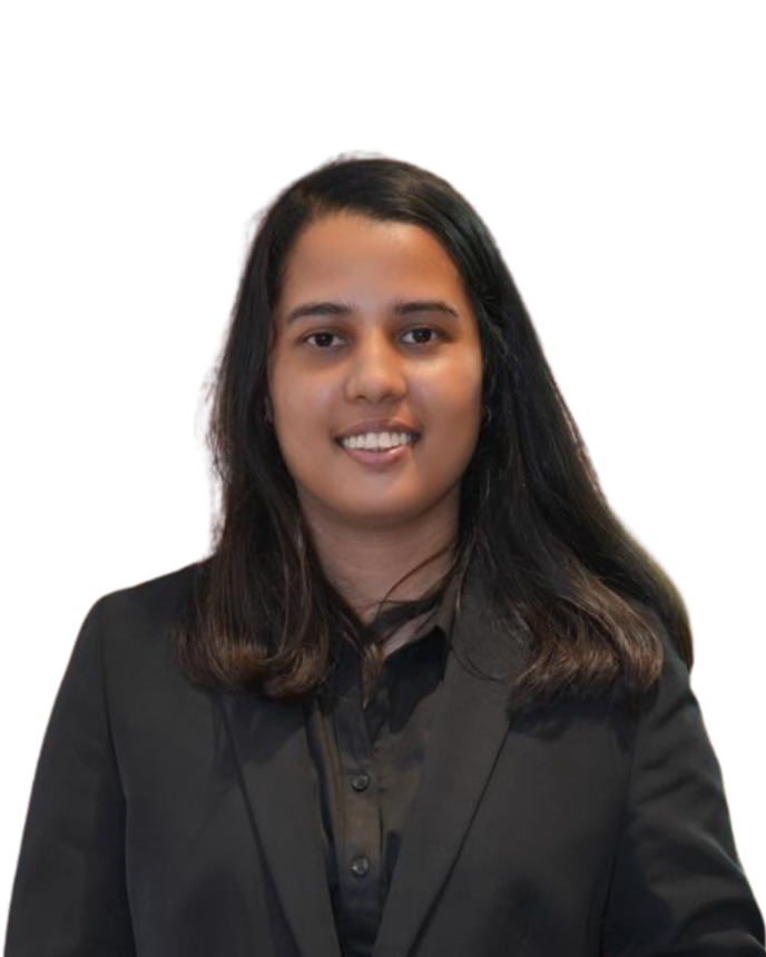 A young woman with shoulder-length dark hair, wearing a black blazer and shirt, smiling at the camera. India and Canada