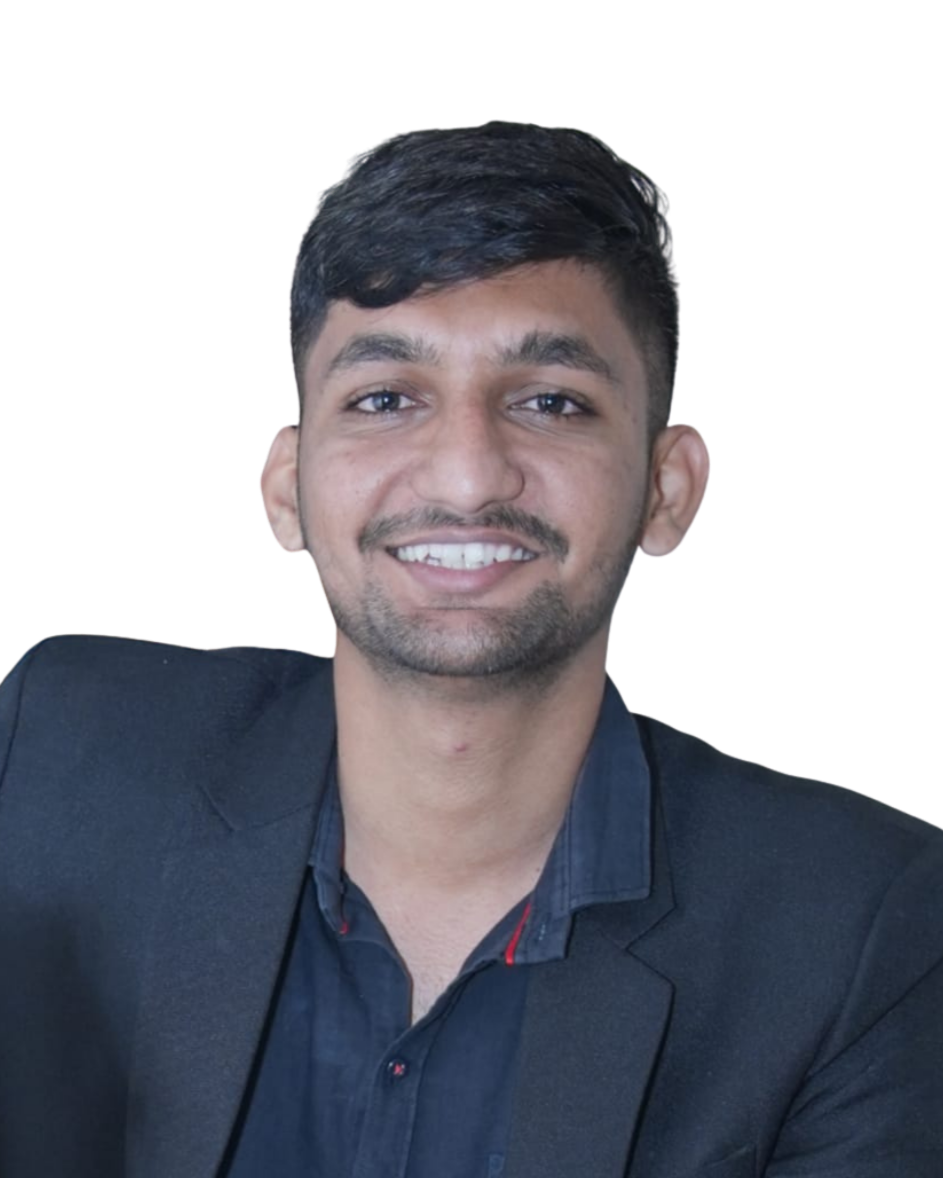 A young man with short dark hair, a trimmed beard, wearing a black blazer over a dark shirt, smiling and looking directly at the camera. India and Canada