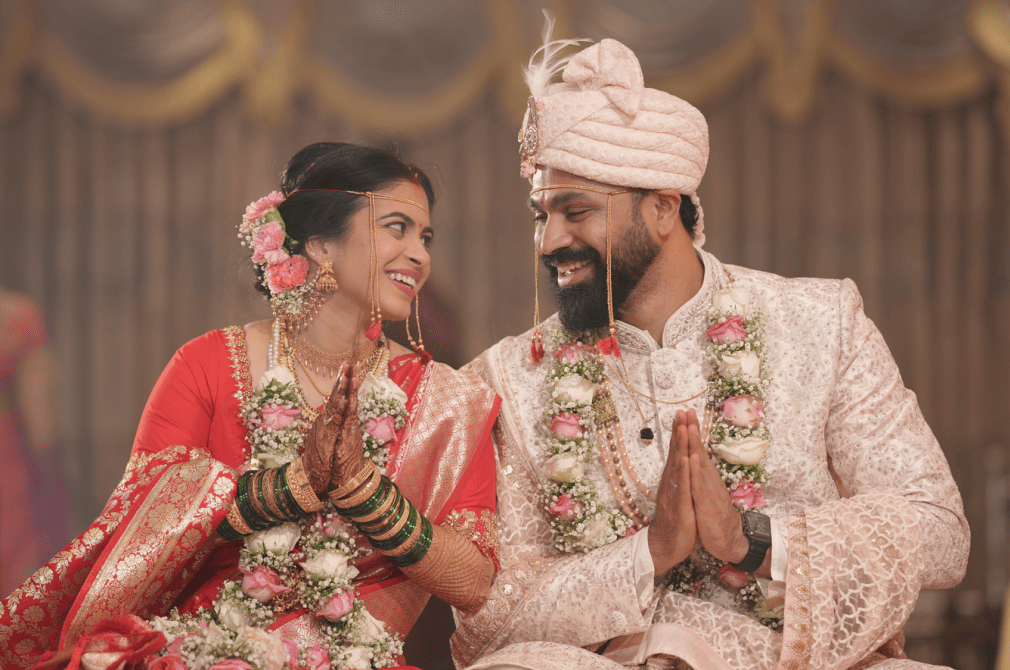 Indian bride and groom in traditional attire, smiling and holding hands during their wedding ceremony. India and Canada