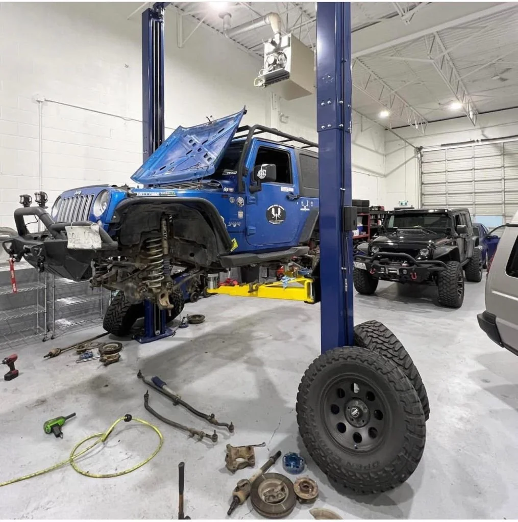 Lifted Jeep 4x4 receiving off road maintenance on a lift at Black Bear Auto