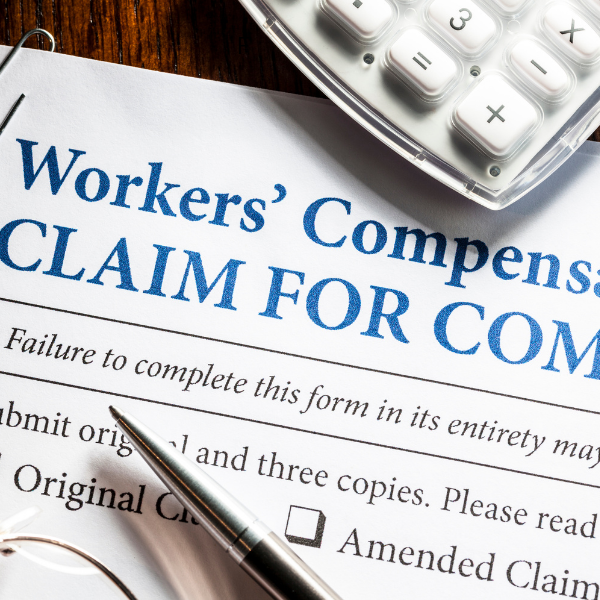Workers' Compensation claim form with a pen on top and a calculator in the background.