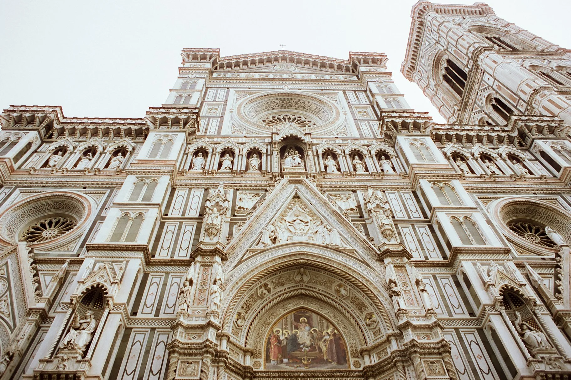 Facade of a detailed, ornate Gothic-style cathedral with statues, arches, and a painted altar inside.