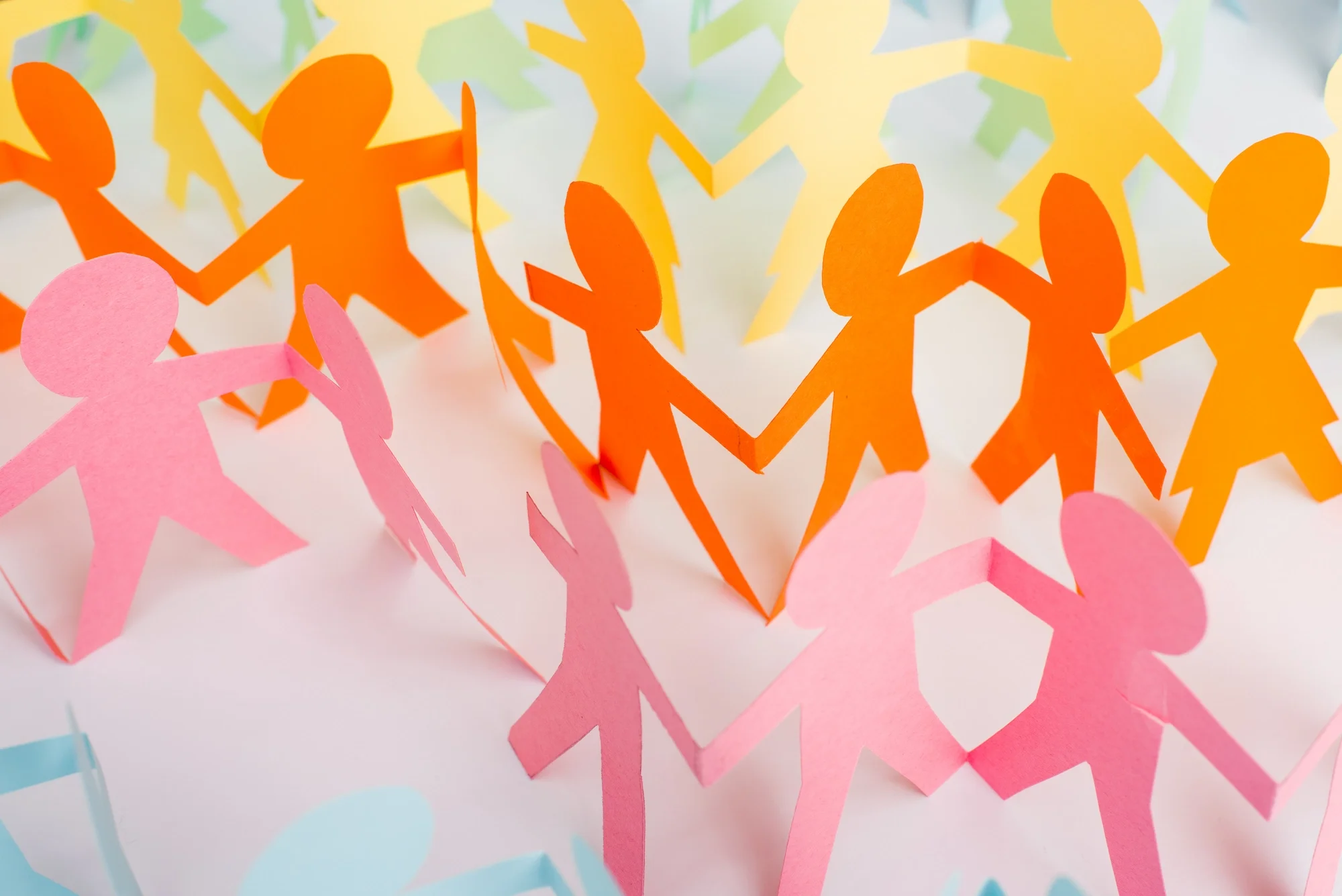 Colorful paper cutout chain of pink, orange, yellow, green, and blue people shapes linked together.