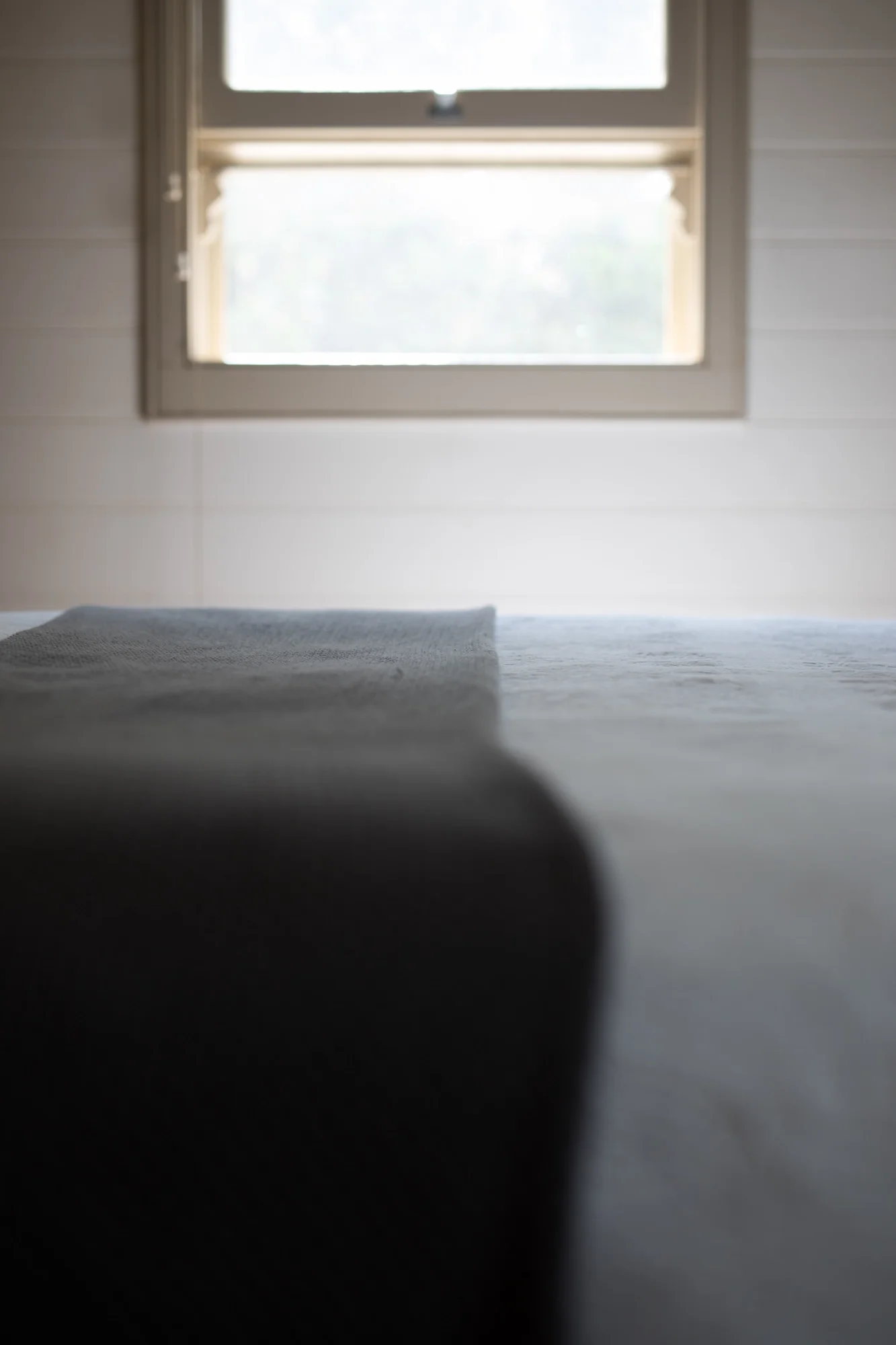 Close-up of a window with some light shining through, with a soft fabric surface visible in the foreground.