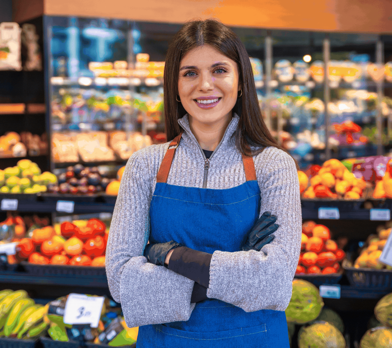 Smiling woman handling produce in a grocery store.