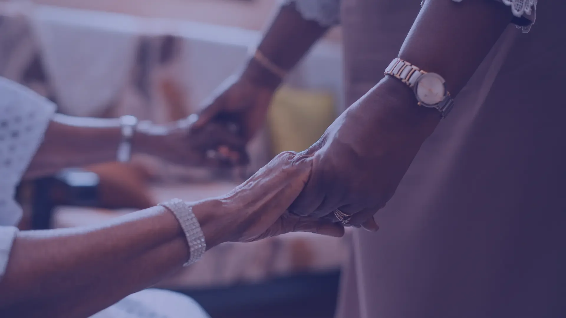 A patient with an IV drip in their hand being cared for by a healthcare professional, possibly a nurse, in a medical setting.