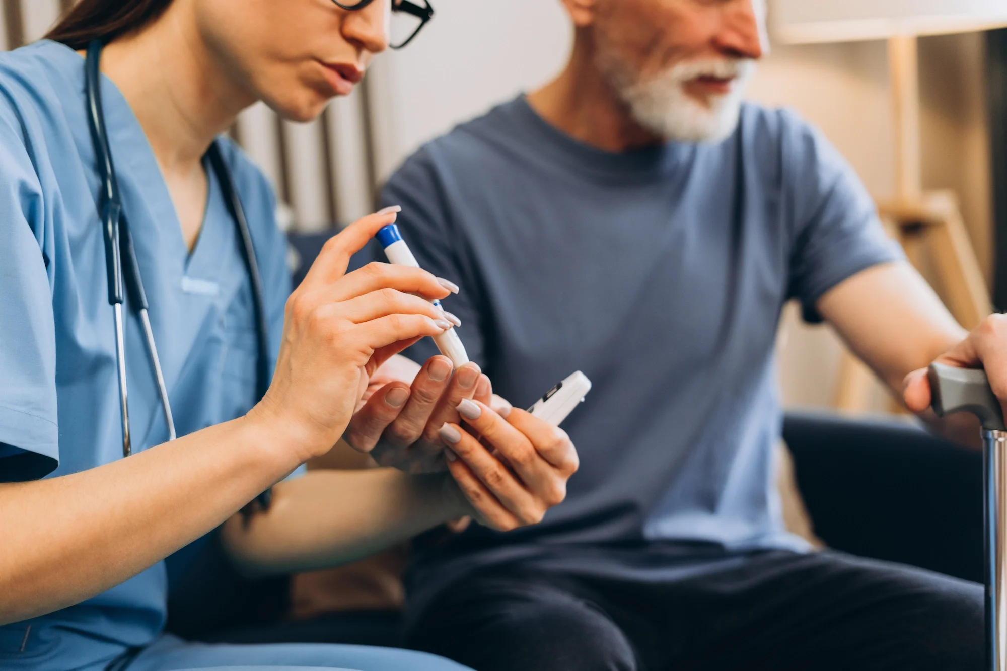 Nurse in scrubs holding a test tube while sitting next to a man in casual clothing, both engaged in a medical or health-related activity.