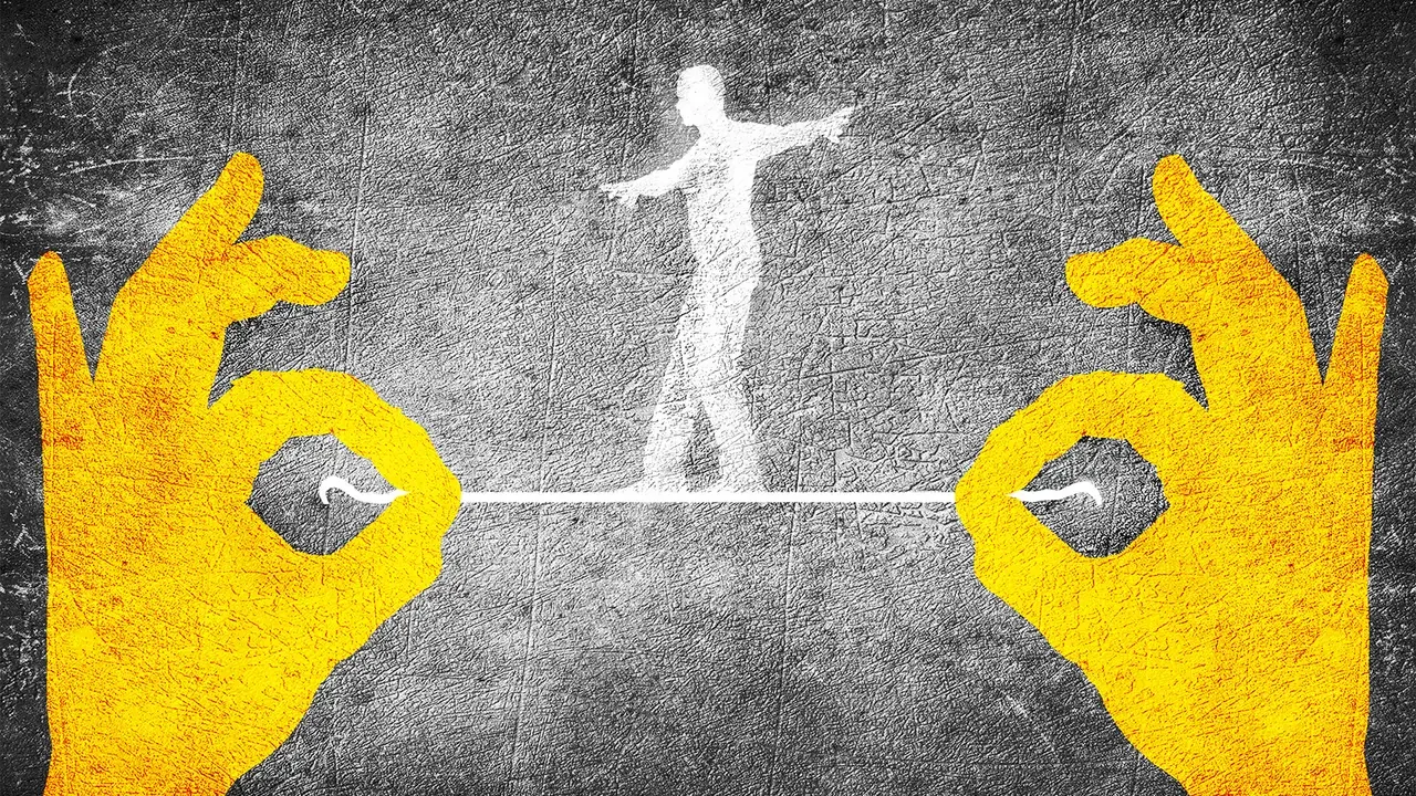 Two yellow hands making an OK gesture with fingers touching to form a circle, on a textured black and gray background with a white chalk drawing of a human figure balancing on a tightrope between the circles.