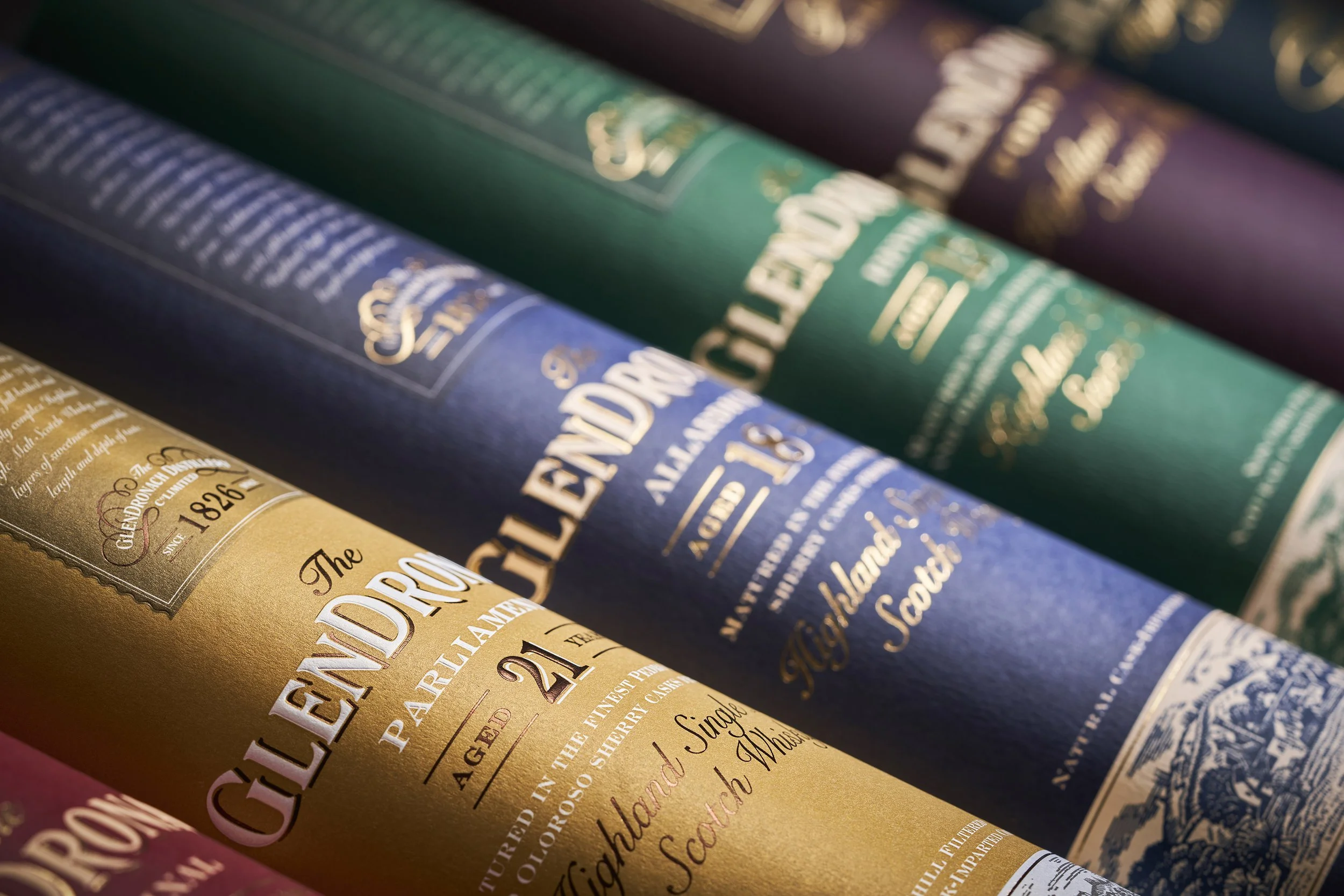 Close-up of colorful whiskey bottle labels with gold and white text, arranged diagonally.