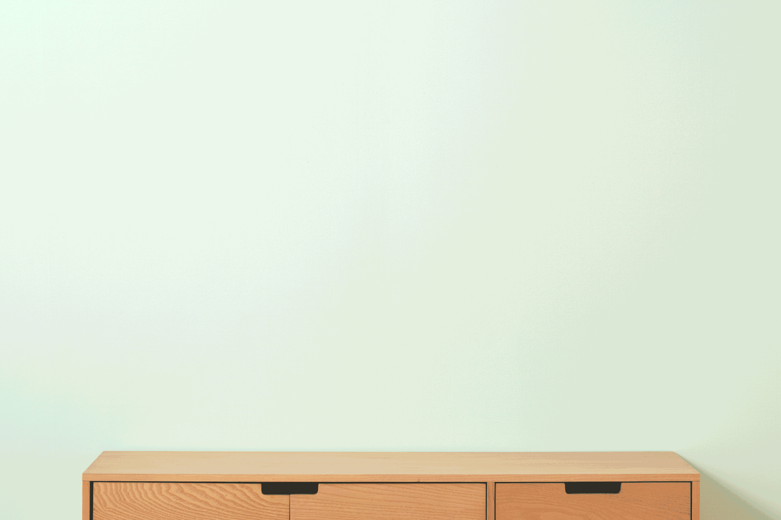 Light green wall with a wooden sideboard at the bottom.