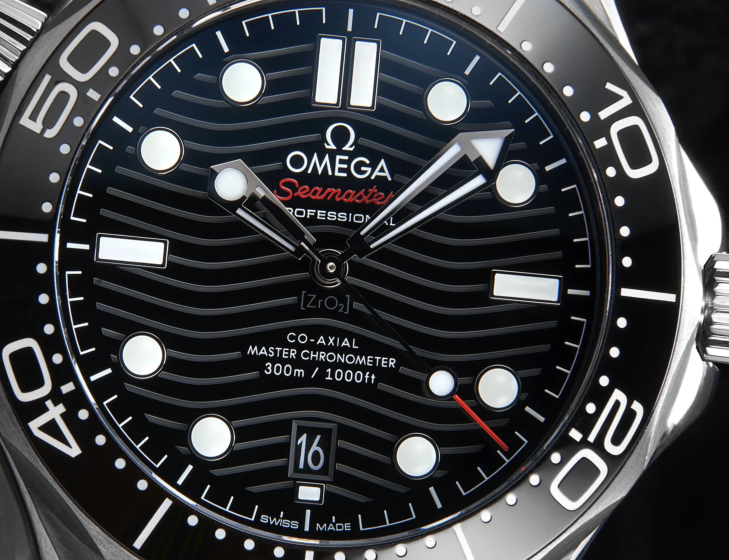 Close-up of an Omega Seamaster Professional wristwatch, black dial with luminous markers, date window at 6 o'clock, and a rotating bezel with minute markers. The watch hands, including the second hand with a red tip, indicate the time.
