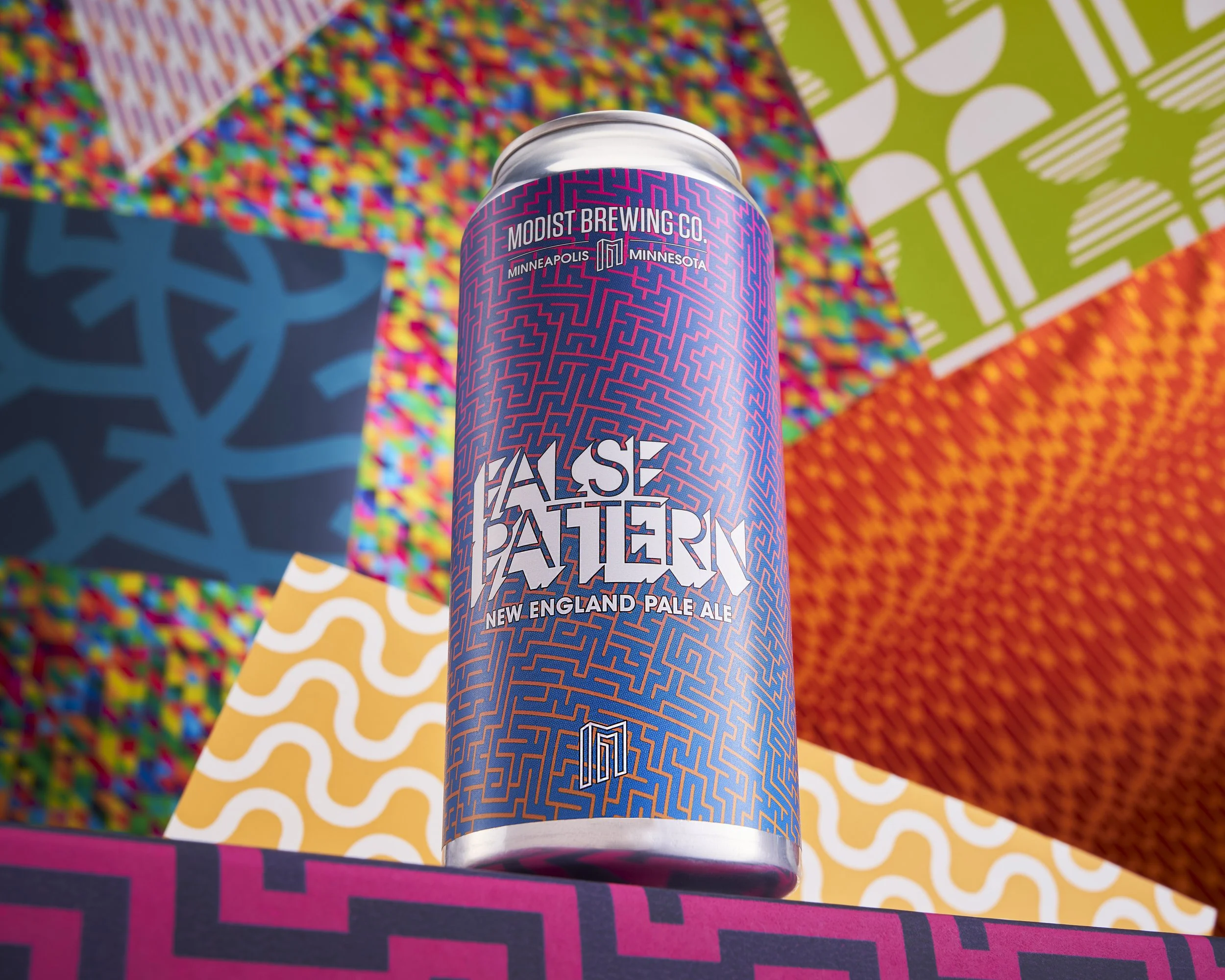 A tall can of 'False Pattern' New England Pale Ale from Modist Brewing Co., with colorful patterned backgrounds.