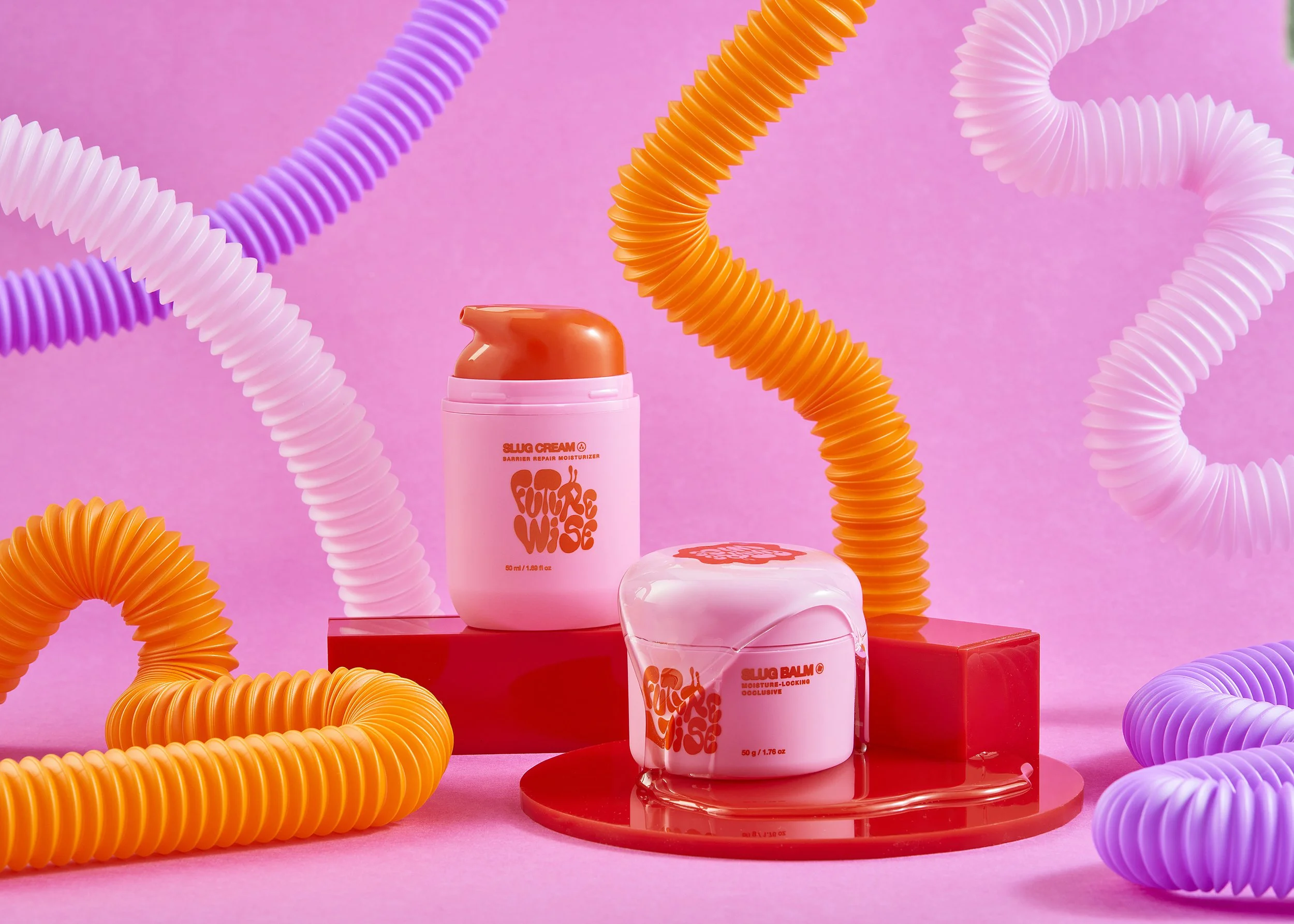 Bright pink background with orange and purple flexible tubes swirling around containers of skincare products, including a tube of moisturizer and a jar of moisturizer-locative cream, displayed on red platforms.