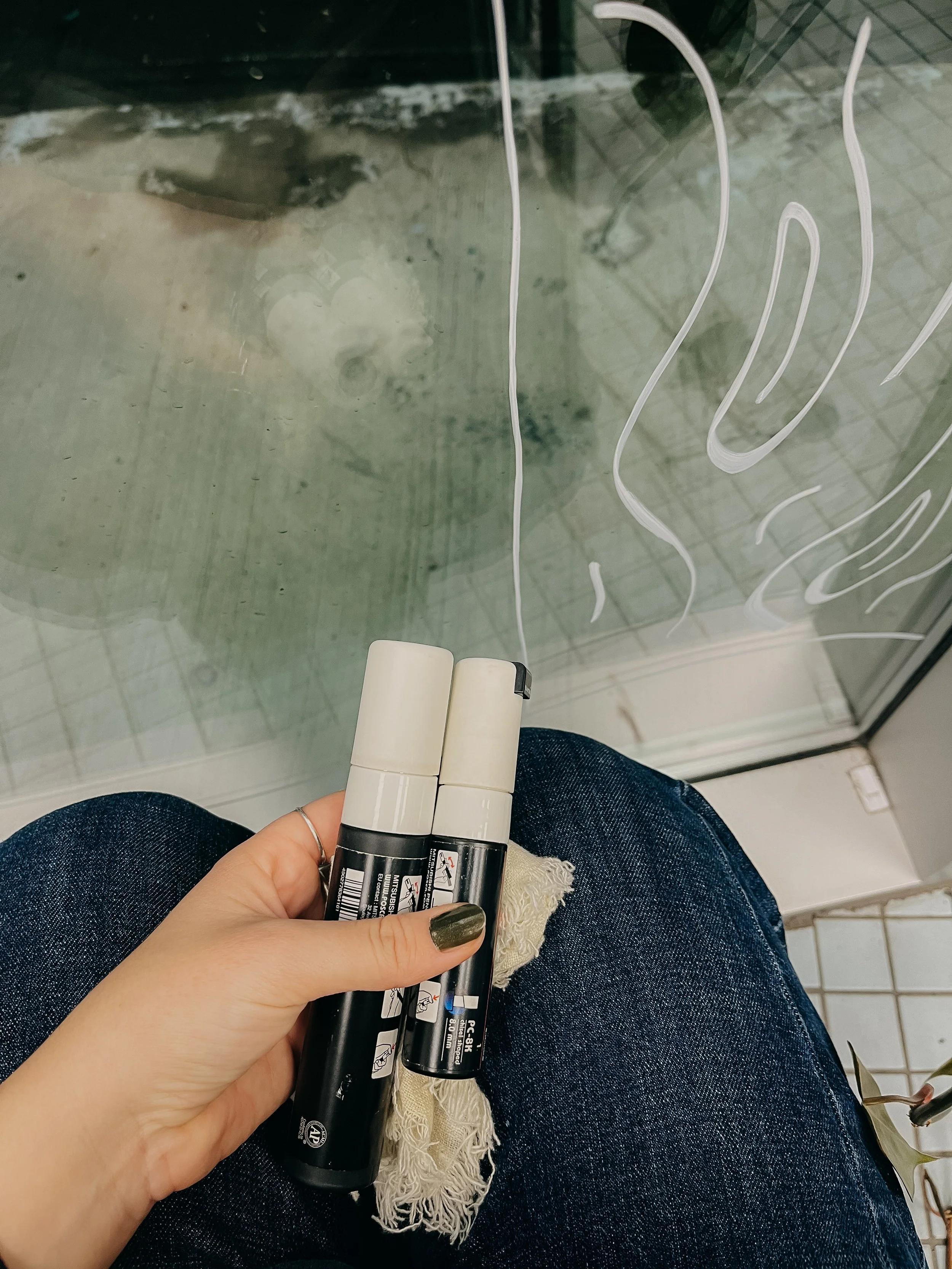 Prise de vue d'une personne assise avec des tubes de marque blanc et noir, devant une vitre avec des dessins blancs.