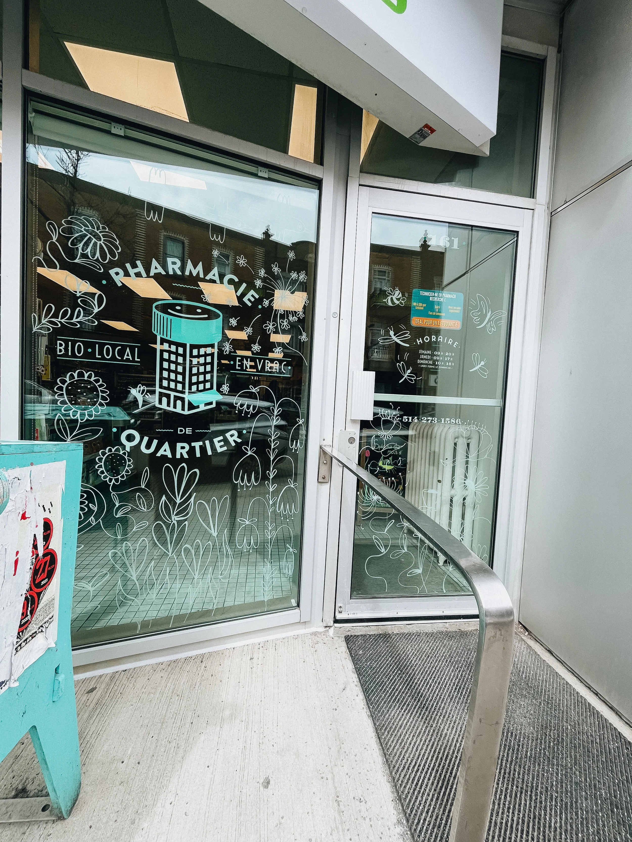 entrée d'une pharmacie avec des décorations florales et un panneau indiquant l'ouverture
