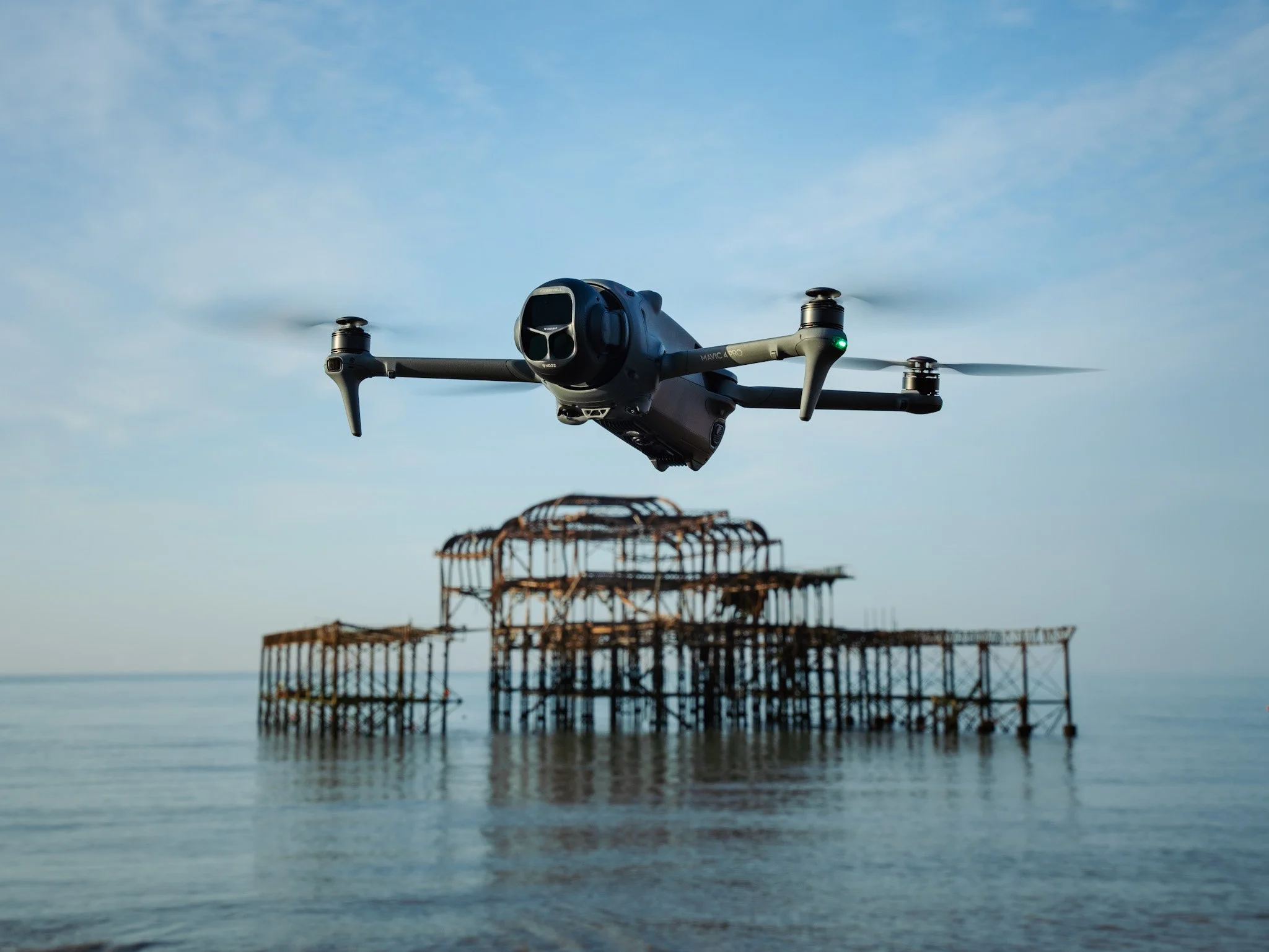A drone flying over a bodies of water near a rusty, abandoned pier.