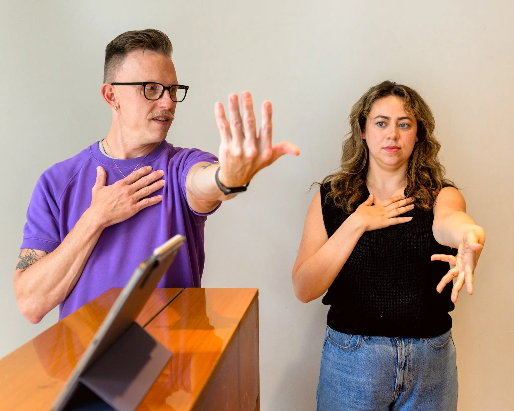 David and Tatiana perform a wrist exercise with their arms out in front of them.