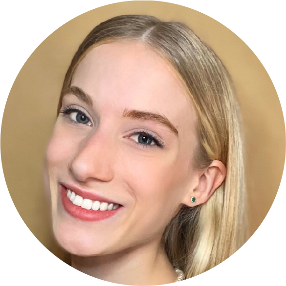 Close-up of a young woman with blonde hair, blue eyes, and a bright smile, wearing a green earring and pearl necklace.